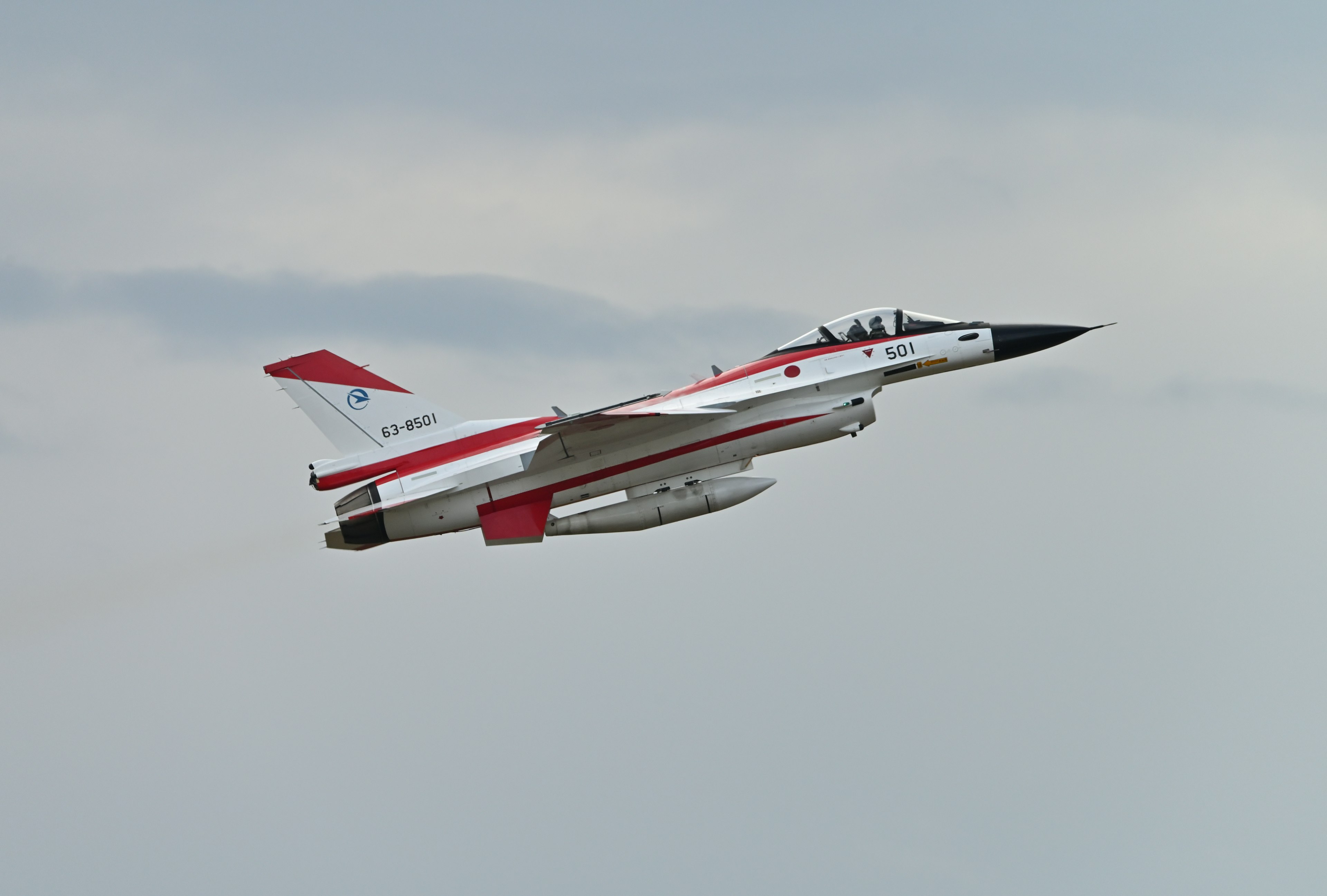 Un avion de chasse rouge et blanc prenant son envol dans le ciel