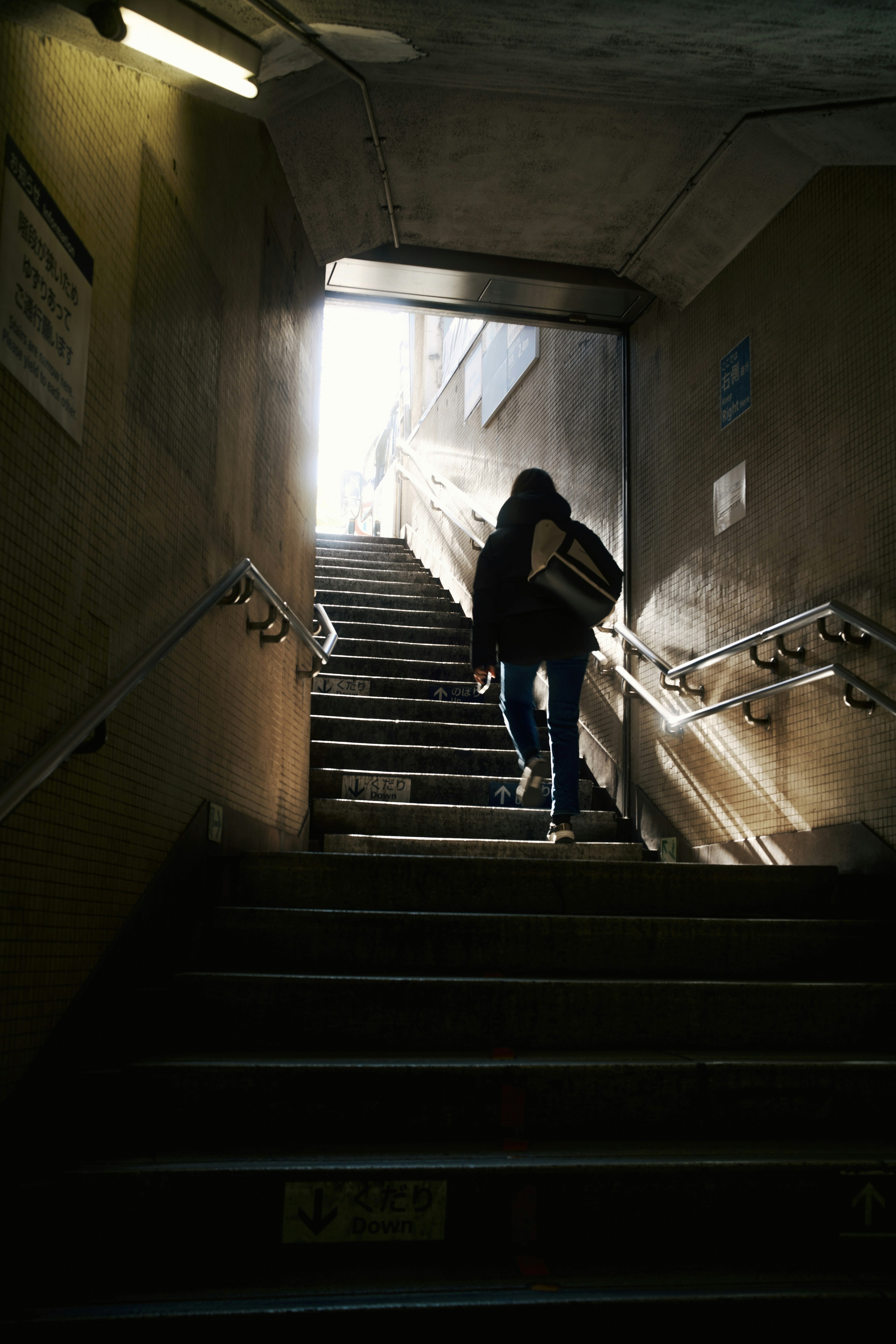 Silueta de una persona subiendo escaleras iluminada por la luz