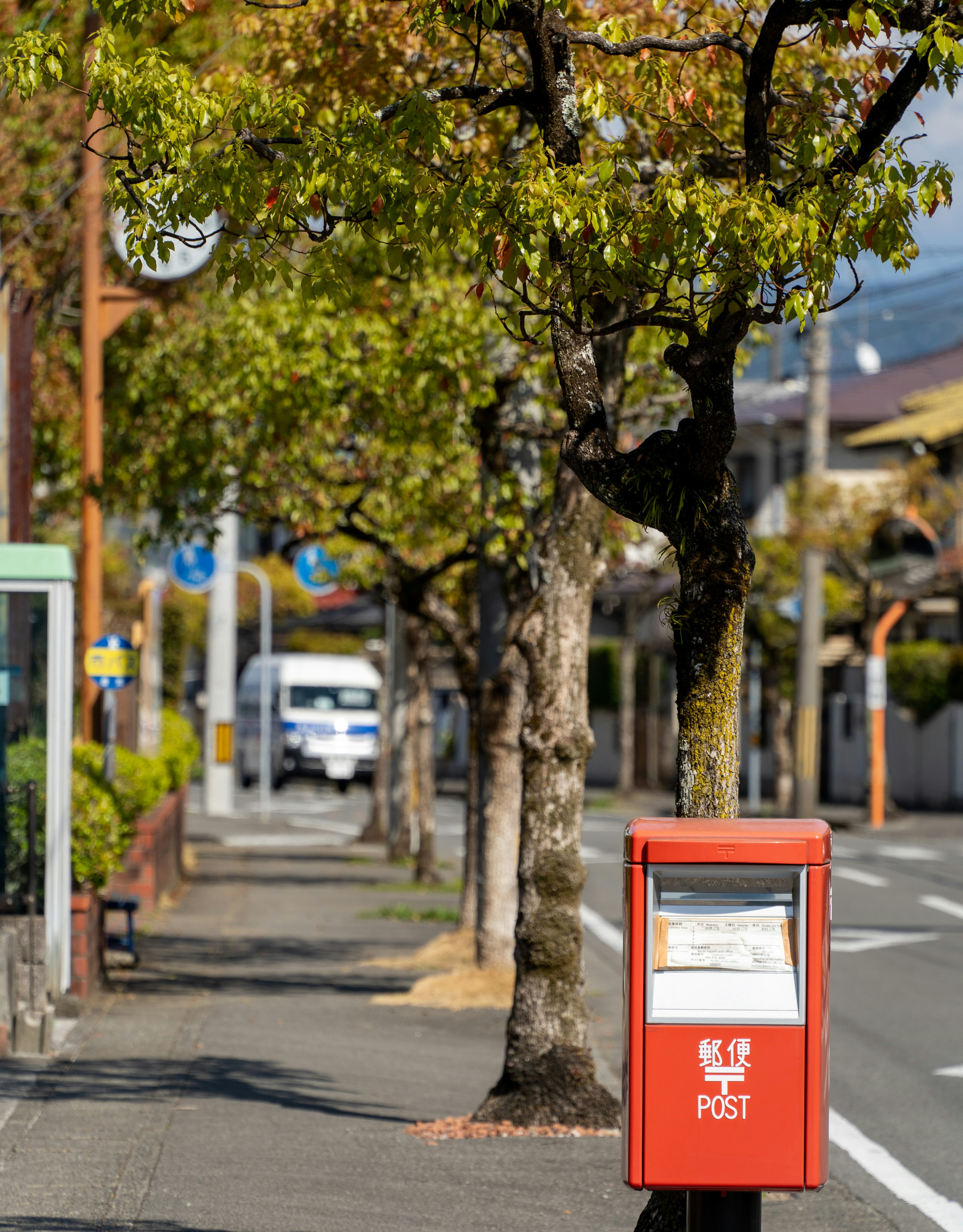 Boîte aux lettres rouge sur la rue avec des arbres verts