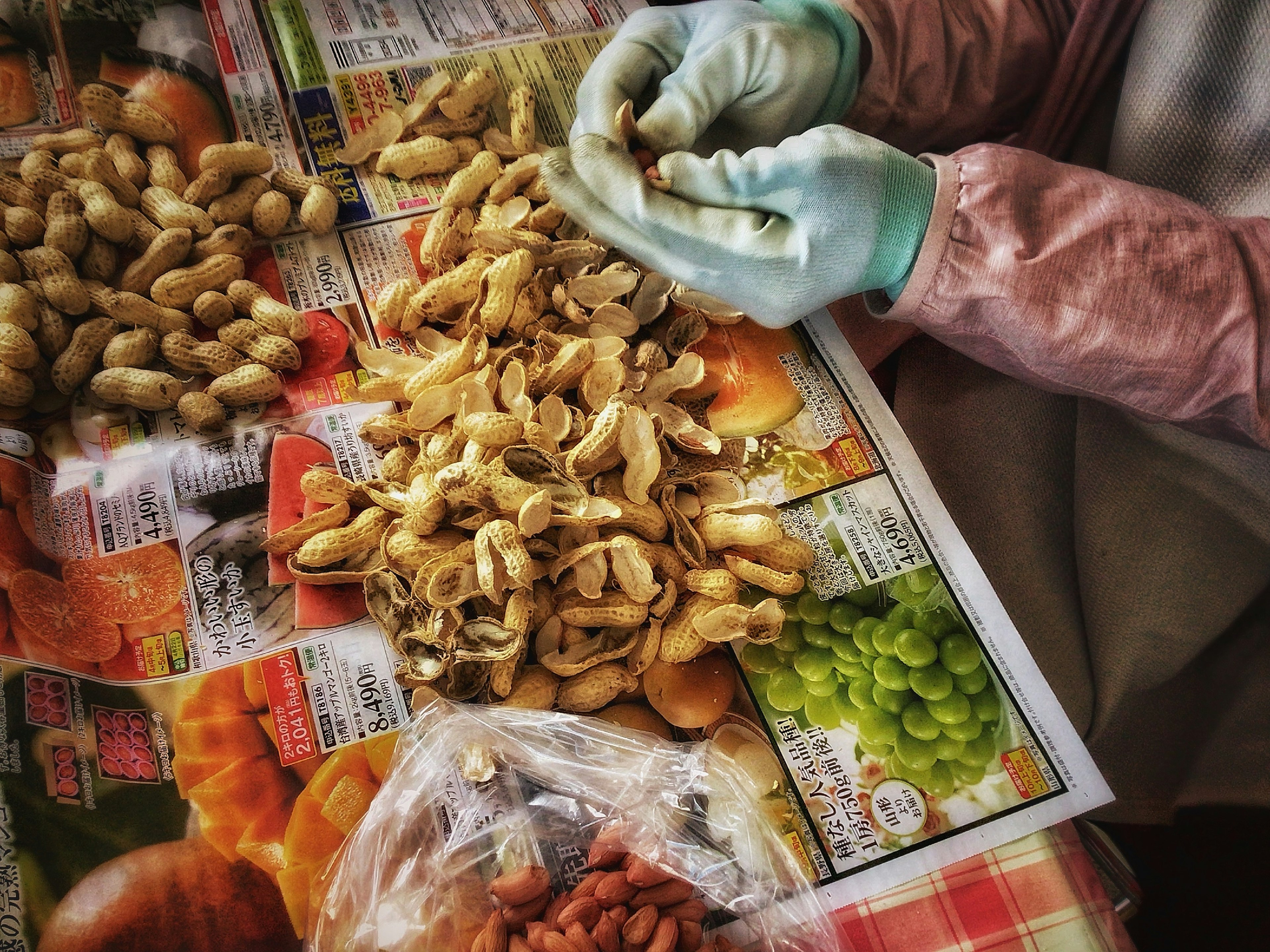 Hands wearing gloves peeling peanuts on a table