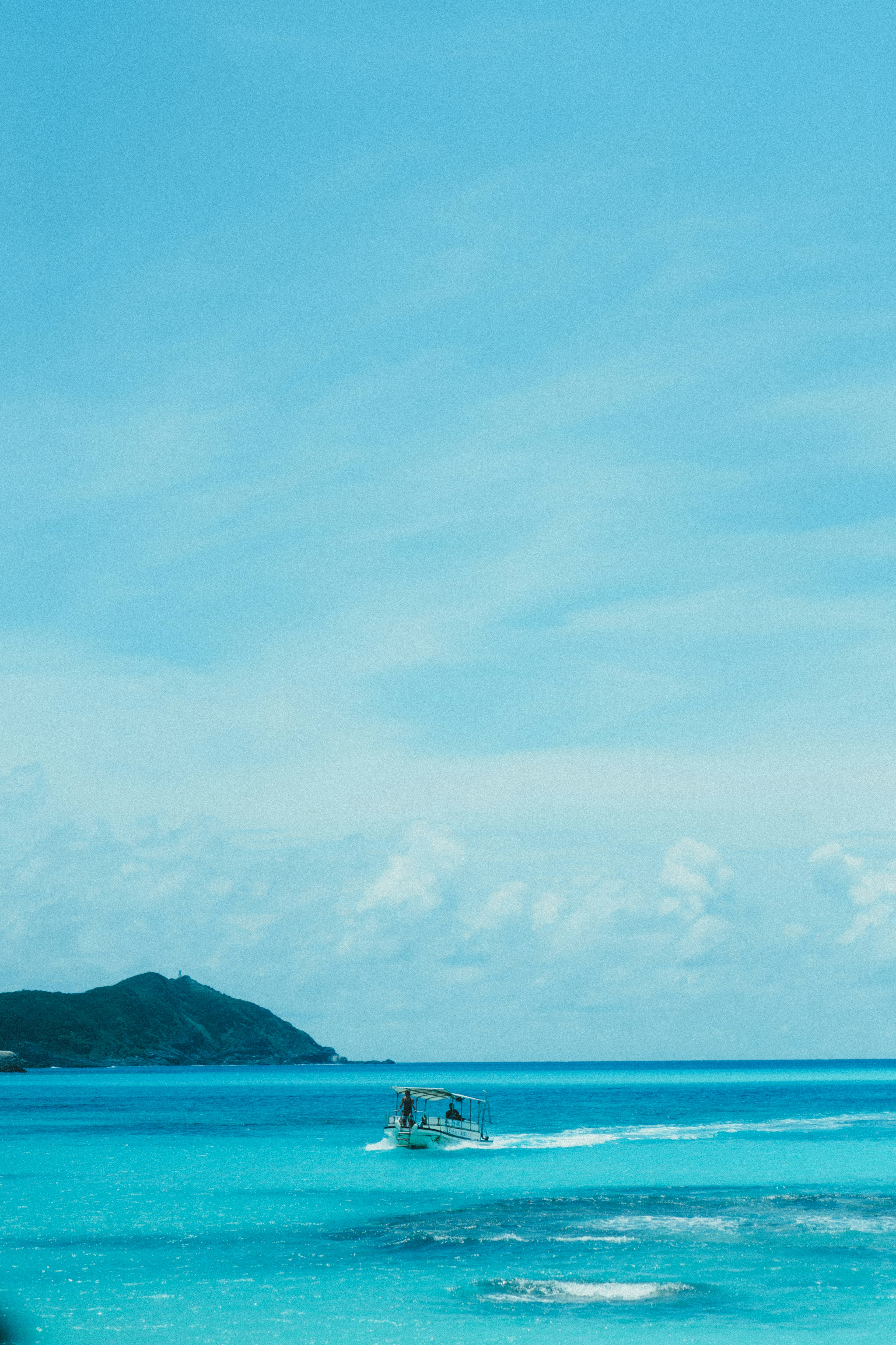 Un petit bateau glissant sur une mer turquoise sous un ciel bleu clair