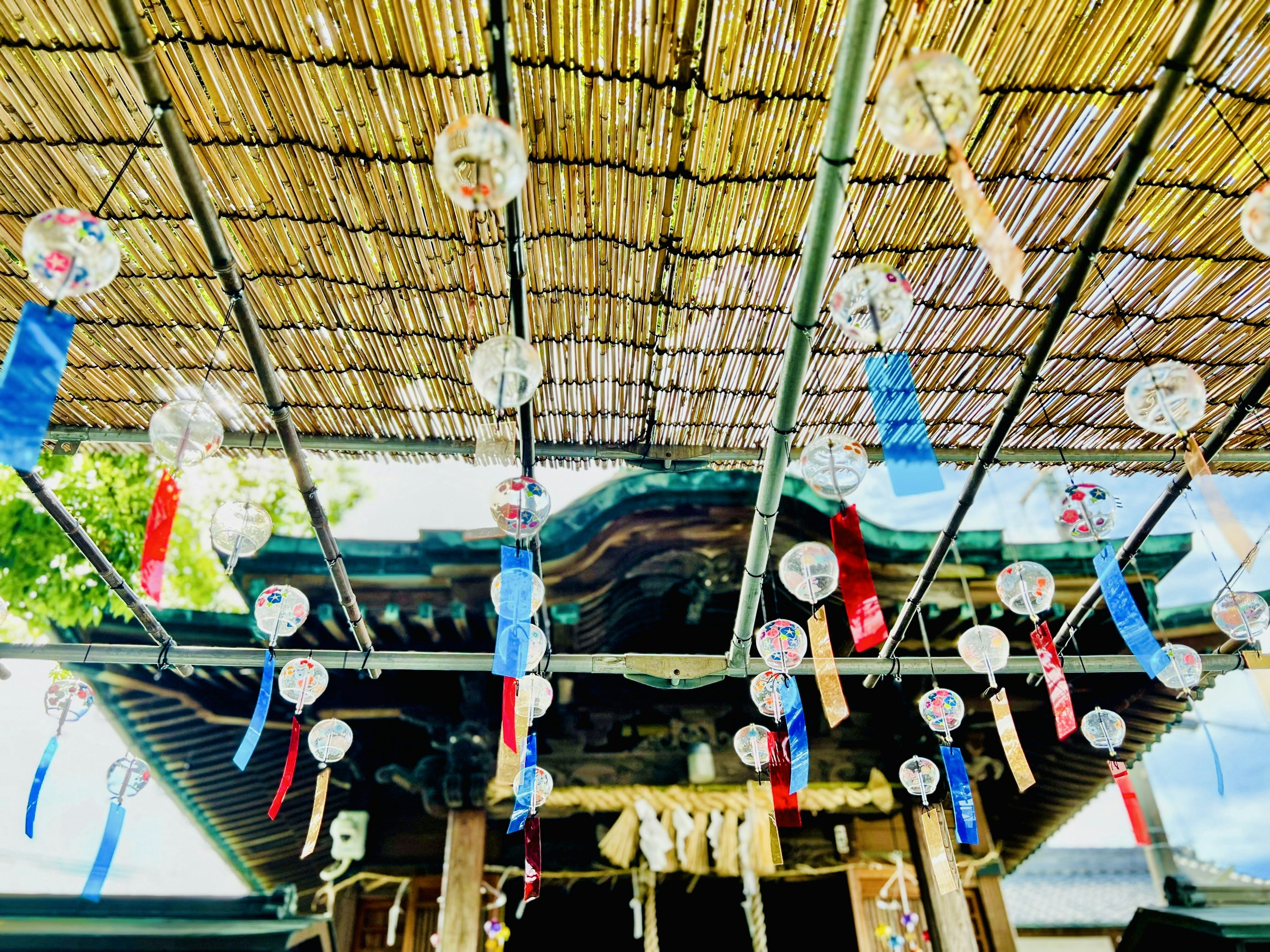 Un santuario con campanas de viento y cintas de colores colgadas bajo un techo de bambú