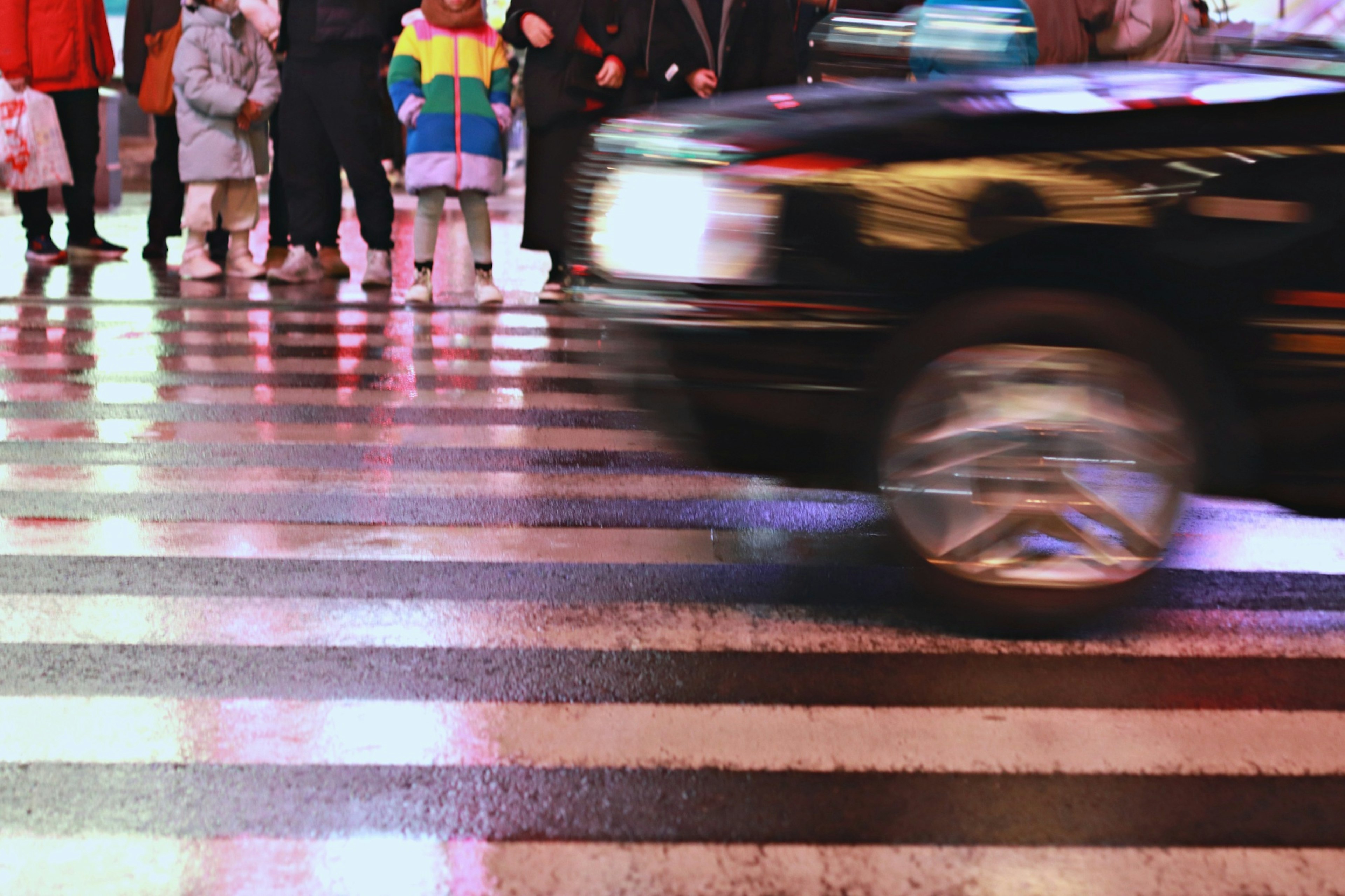 Un taxi passant par un passage piéton avec une foule de personnes attendant