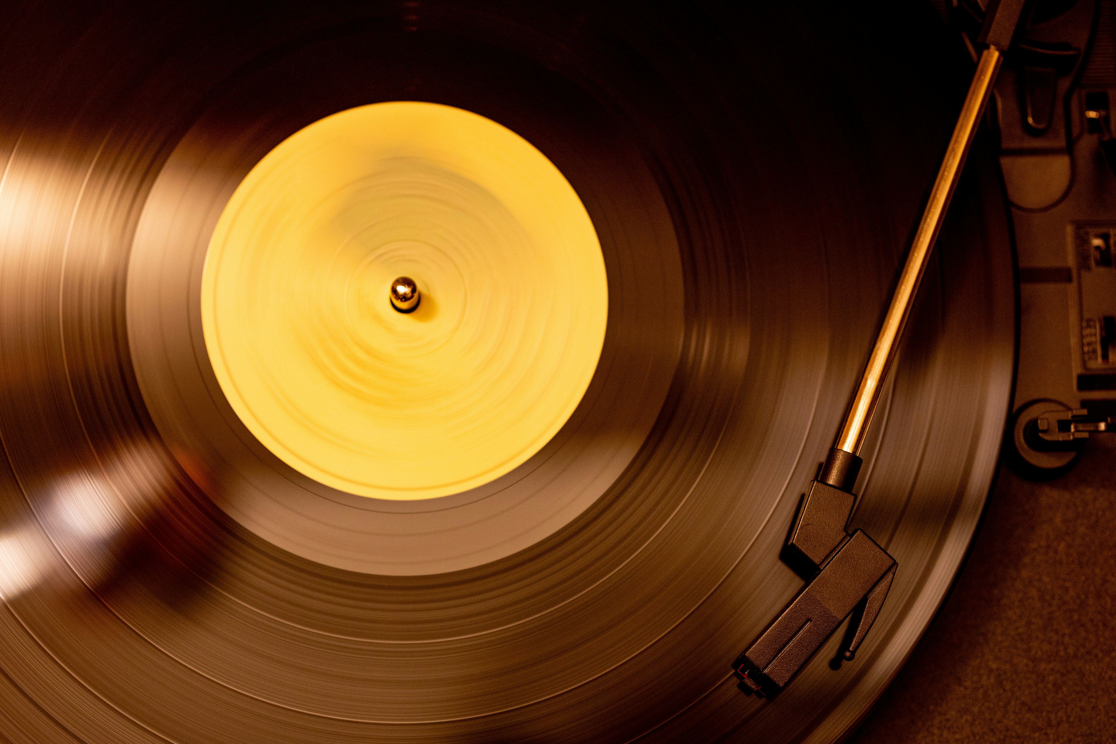 Gros plan d'un disque vinyle tournant sur une platine avec une étiquette jaune et un bras de lecture