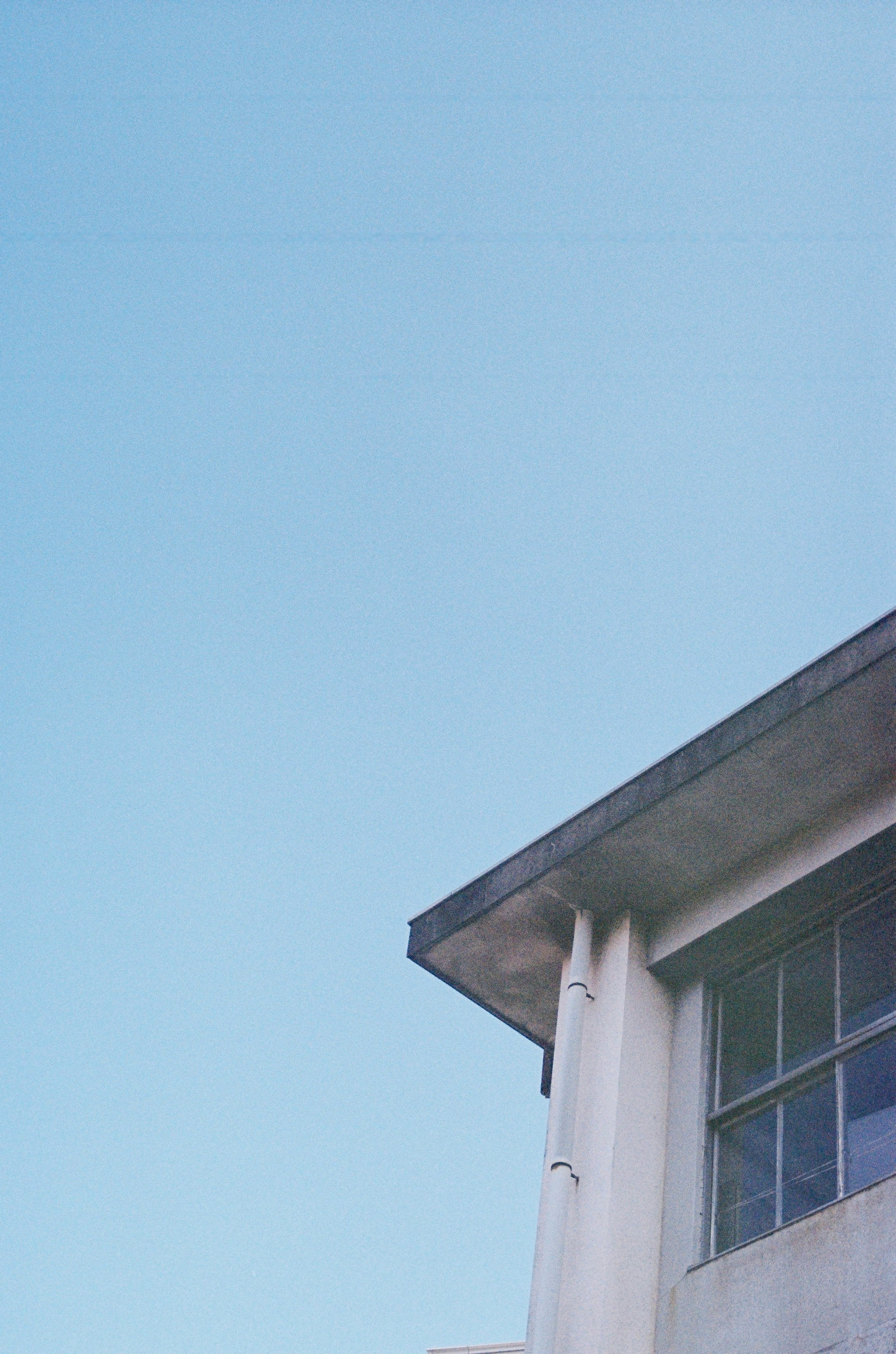 Part of a building and roof under a blue sky