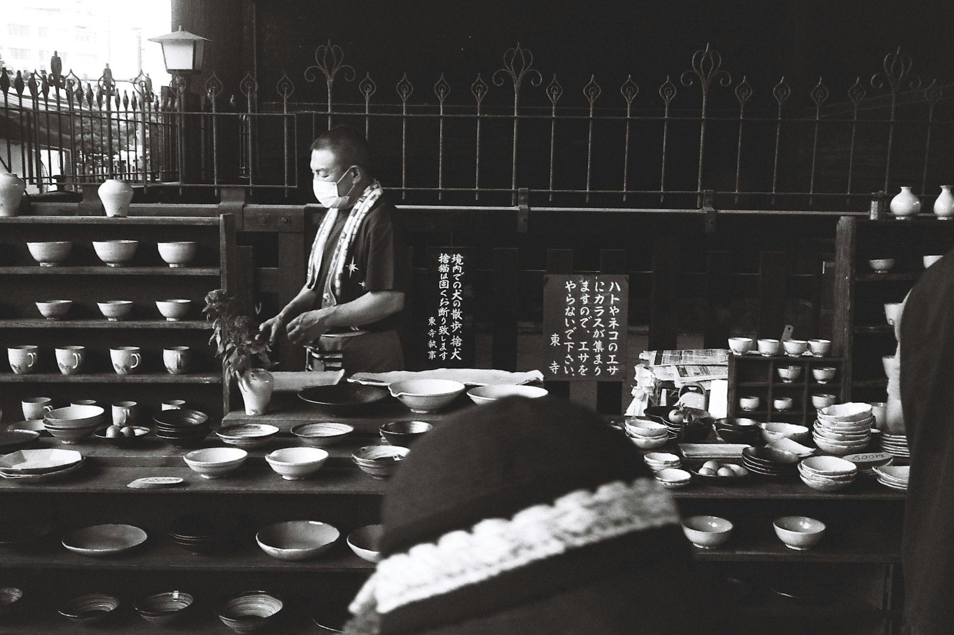 Image en noir et blanc d'un vendeur de poterie avec des plats disposés