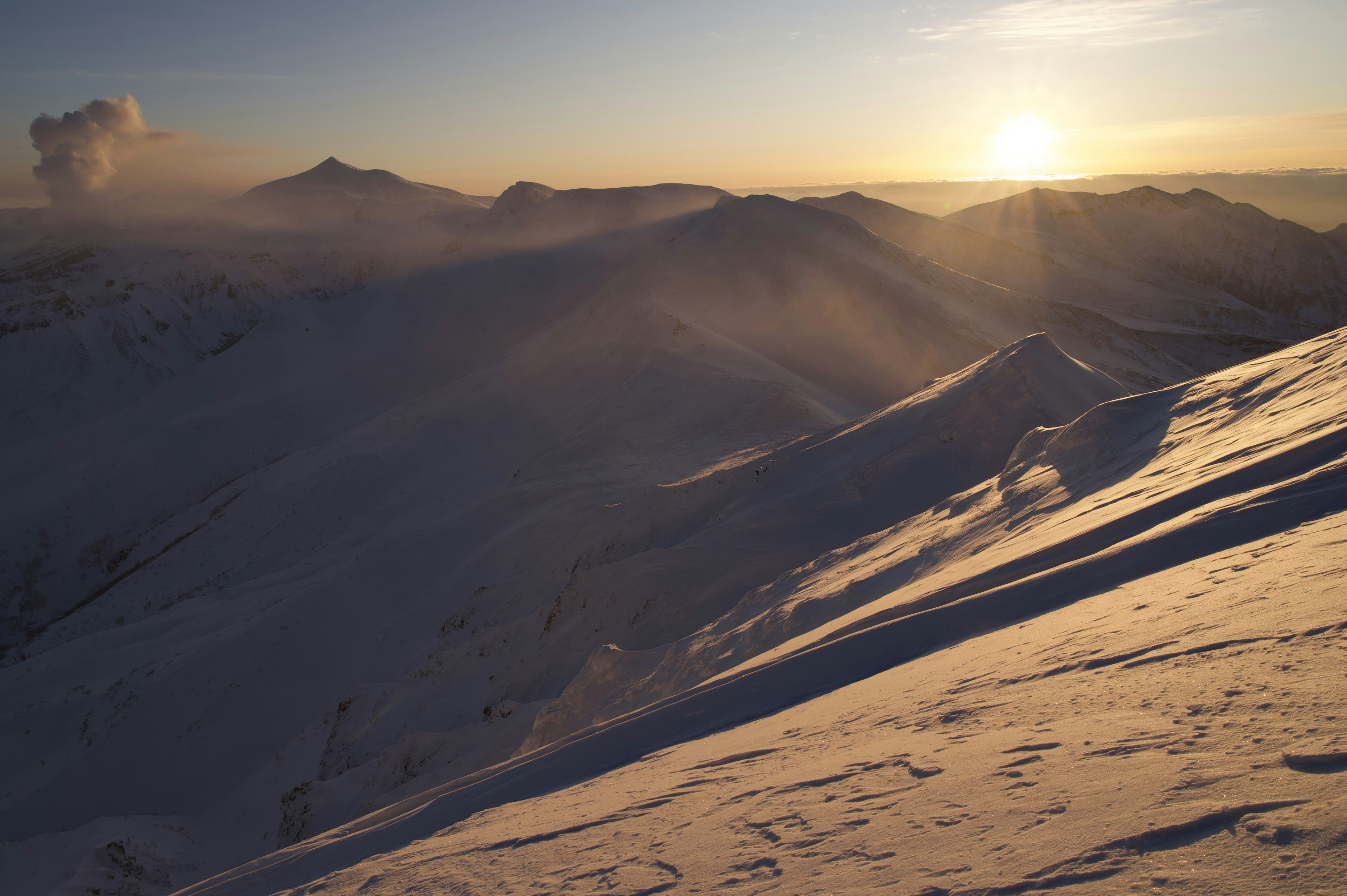 Verschneite Berge mit Sonnenaufgang im Hintergrund