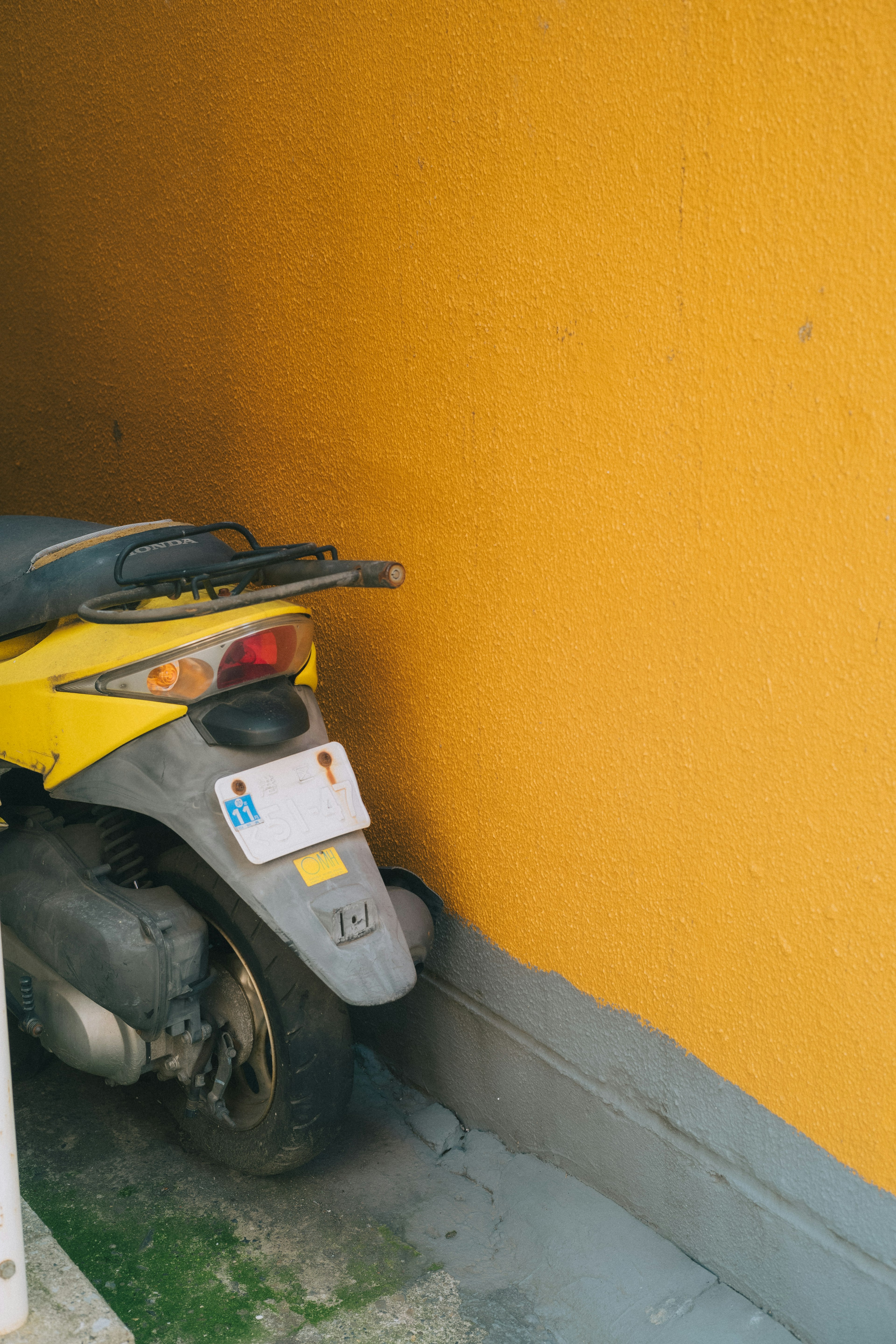 Scooter jaune garé contre un mur orange