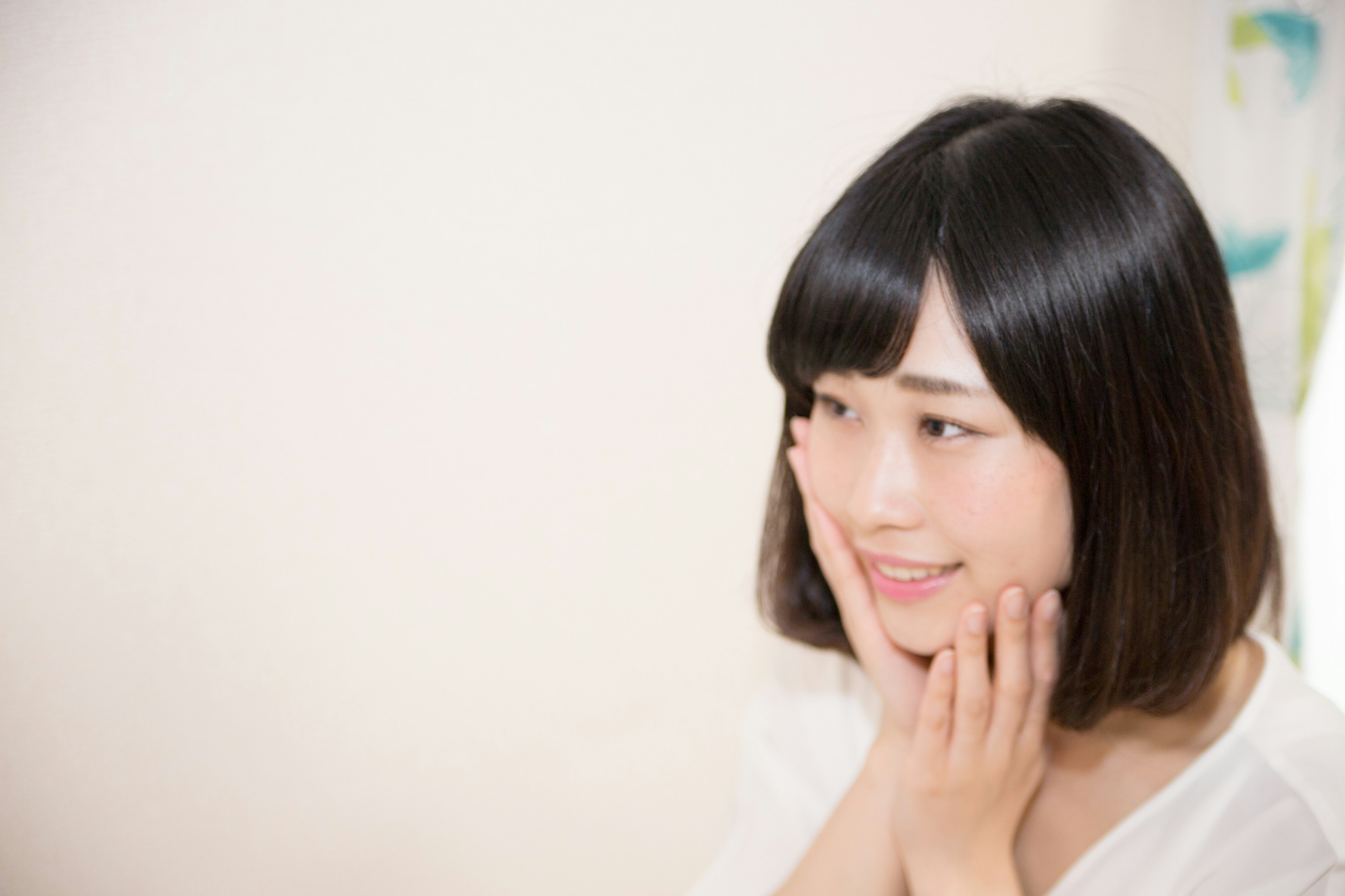 Young woman smiling with hands on her face natural background