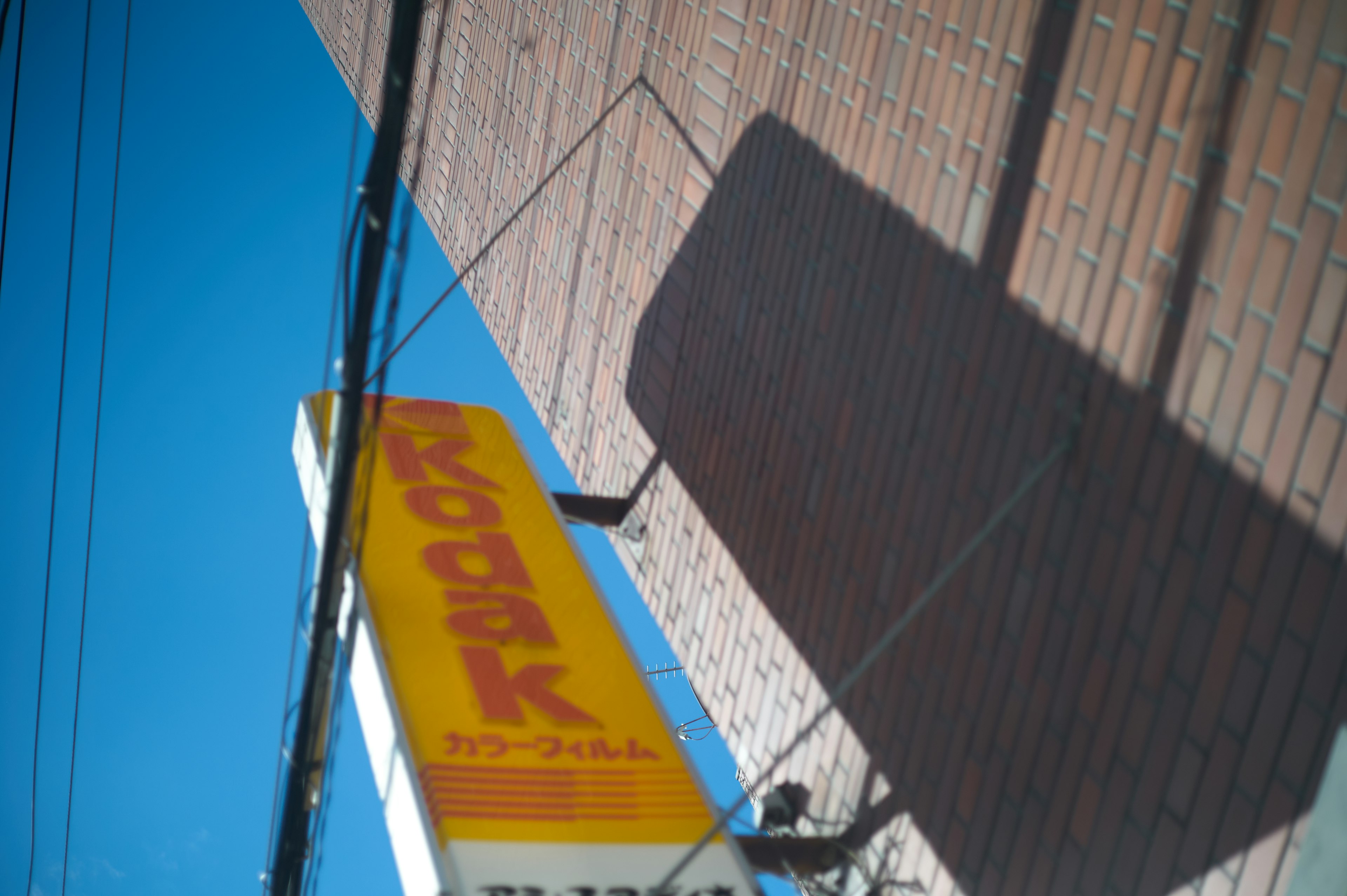 Papan Kodak dengan huruf kuning mencolok di bawah langit biru