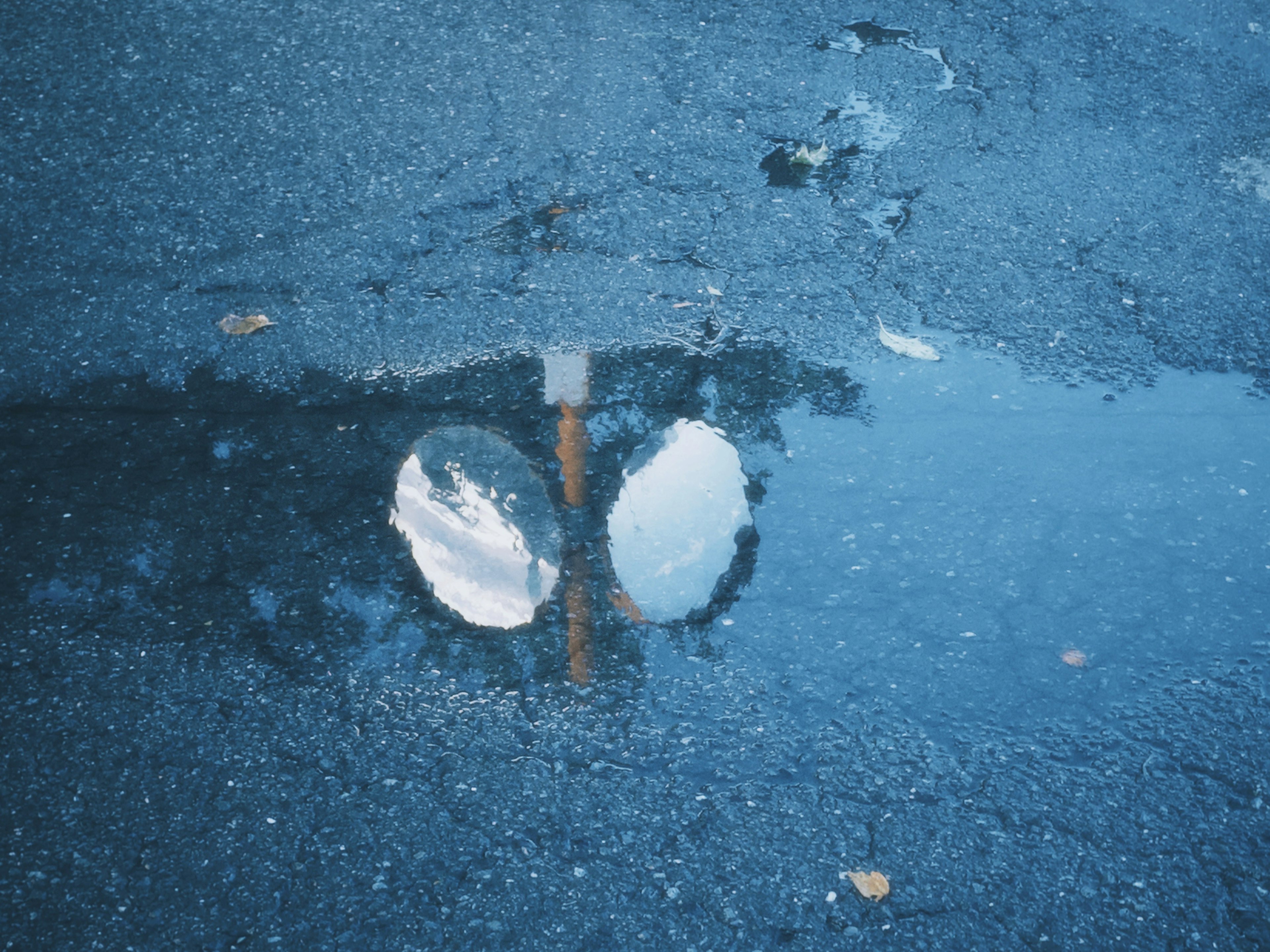 Reflet de nuages blancs et d'un panneau de rue dans une flaque d'eau