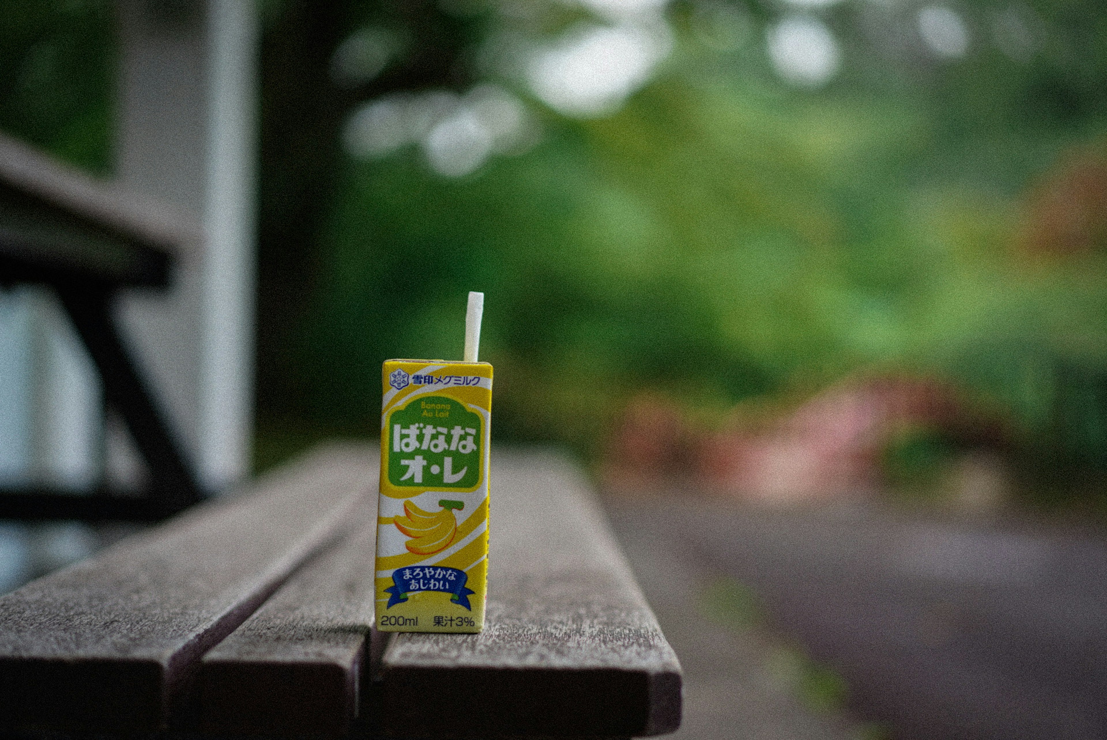 Carton de jus d'orange jaune posé sur une table en bois avec un fond vert