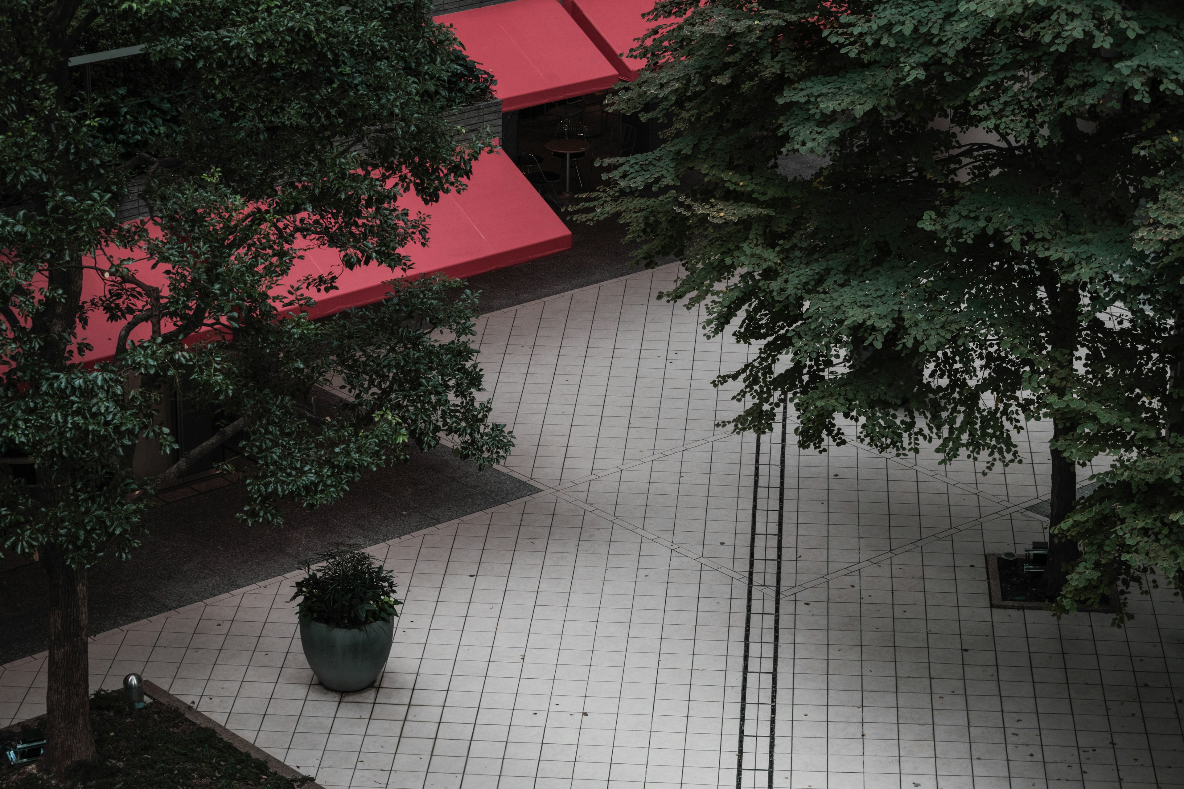 Aerial view of a quiet plaza with red awnings and green trees