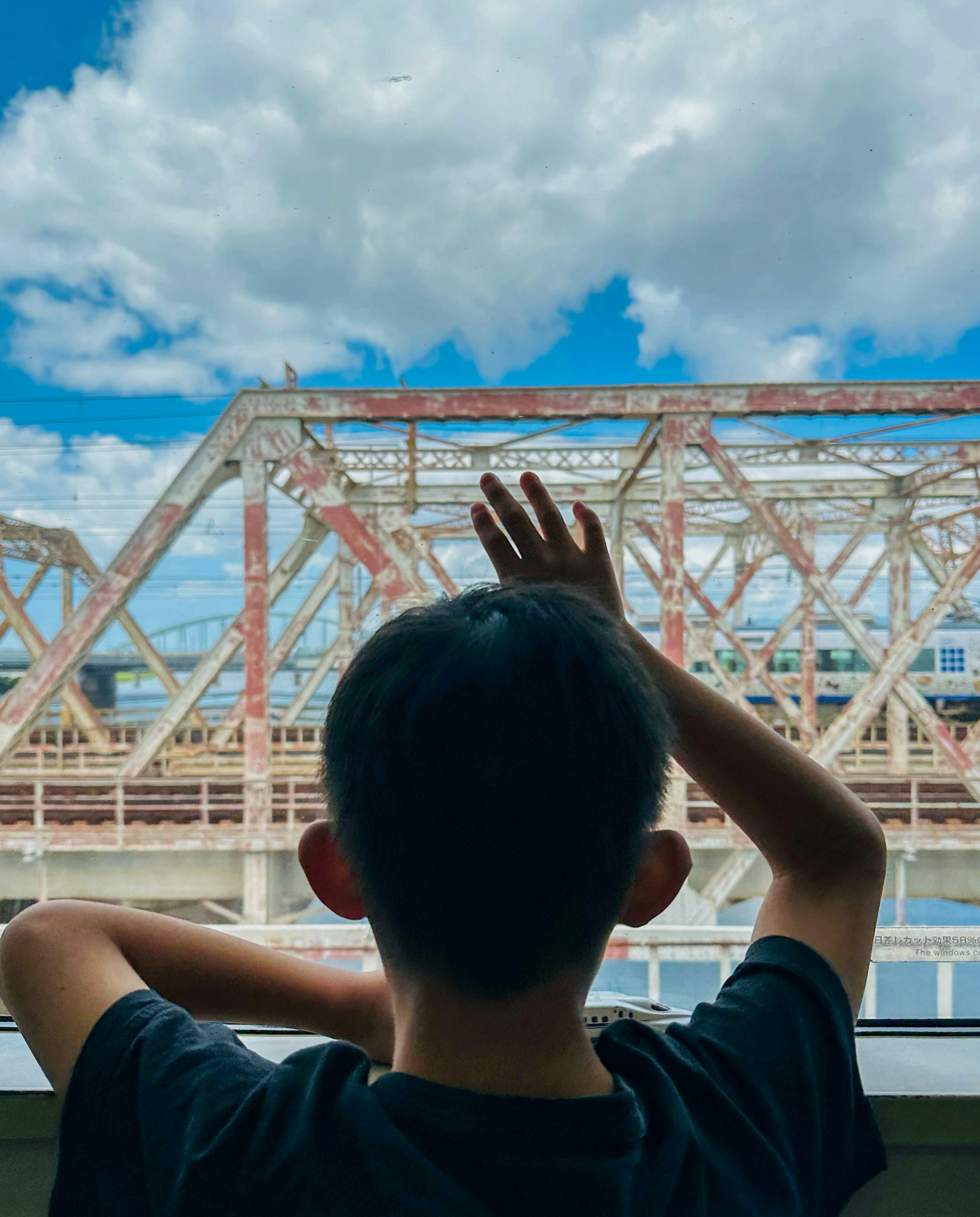 Garçon regardant par la fenêtre avec un pont en vue