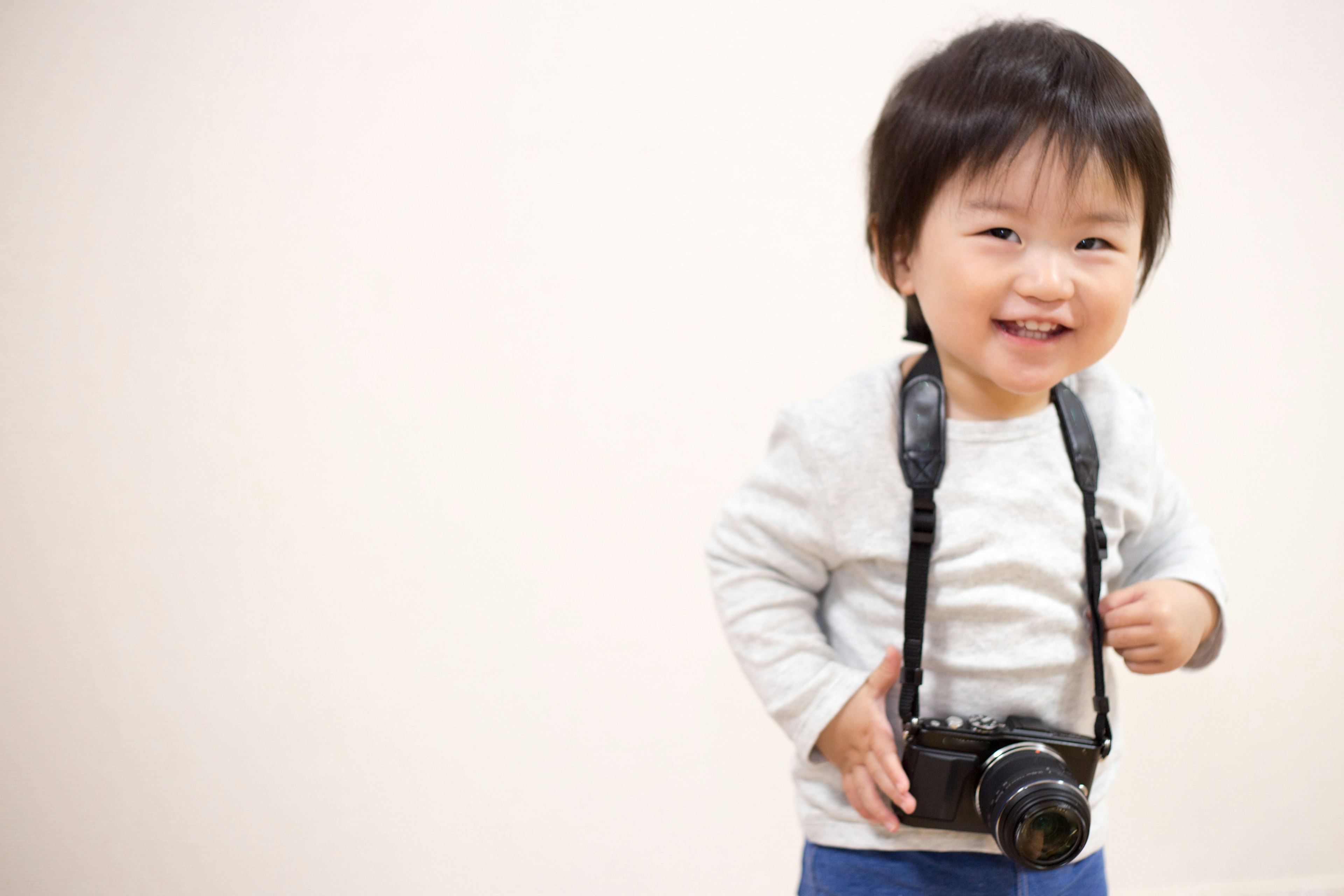 Bambino sorridente con una macchina fotografica davanti a uno sfondo bianco