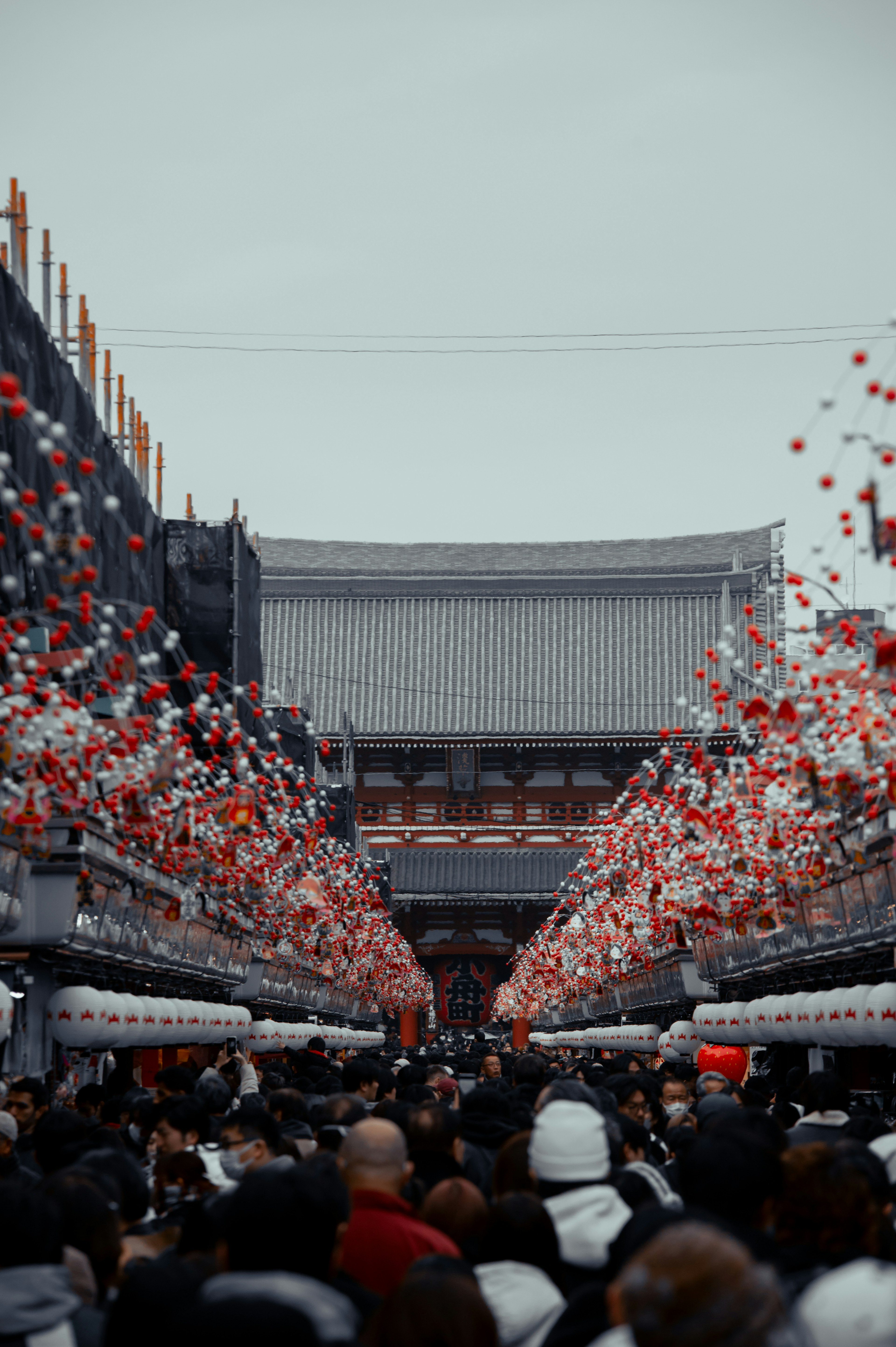 多くの人々が集まる賑やかな市場の通りに赤と白の提灯が飾られた情景