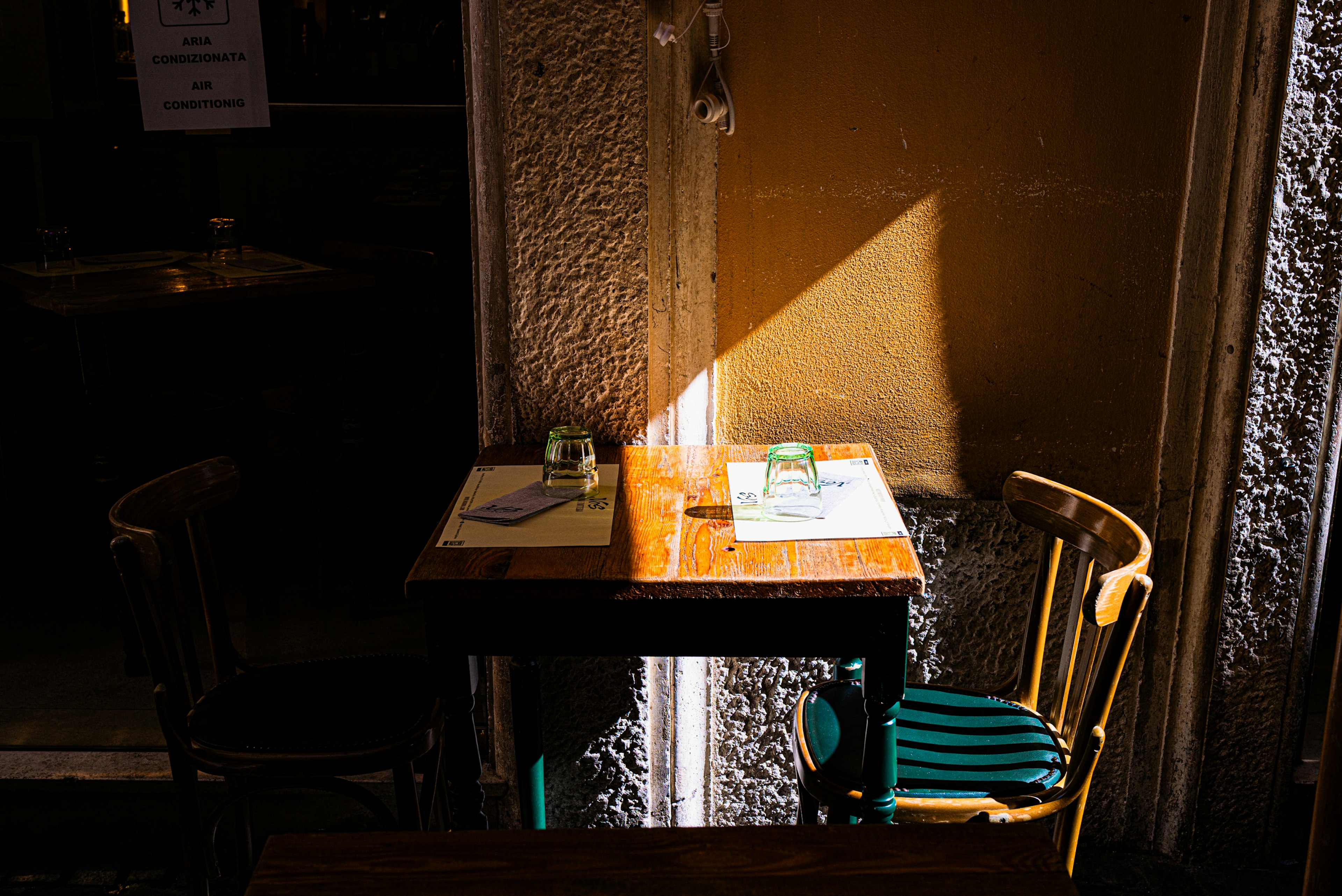 A small café table with a chair illuminated by sunlight