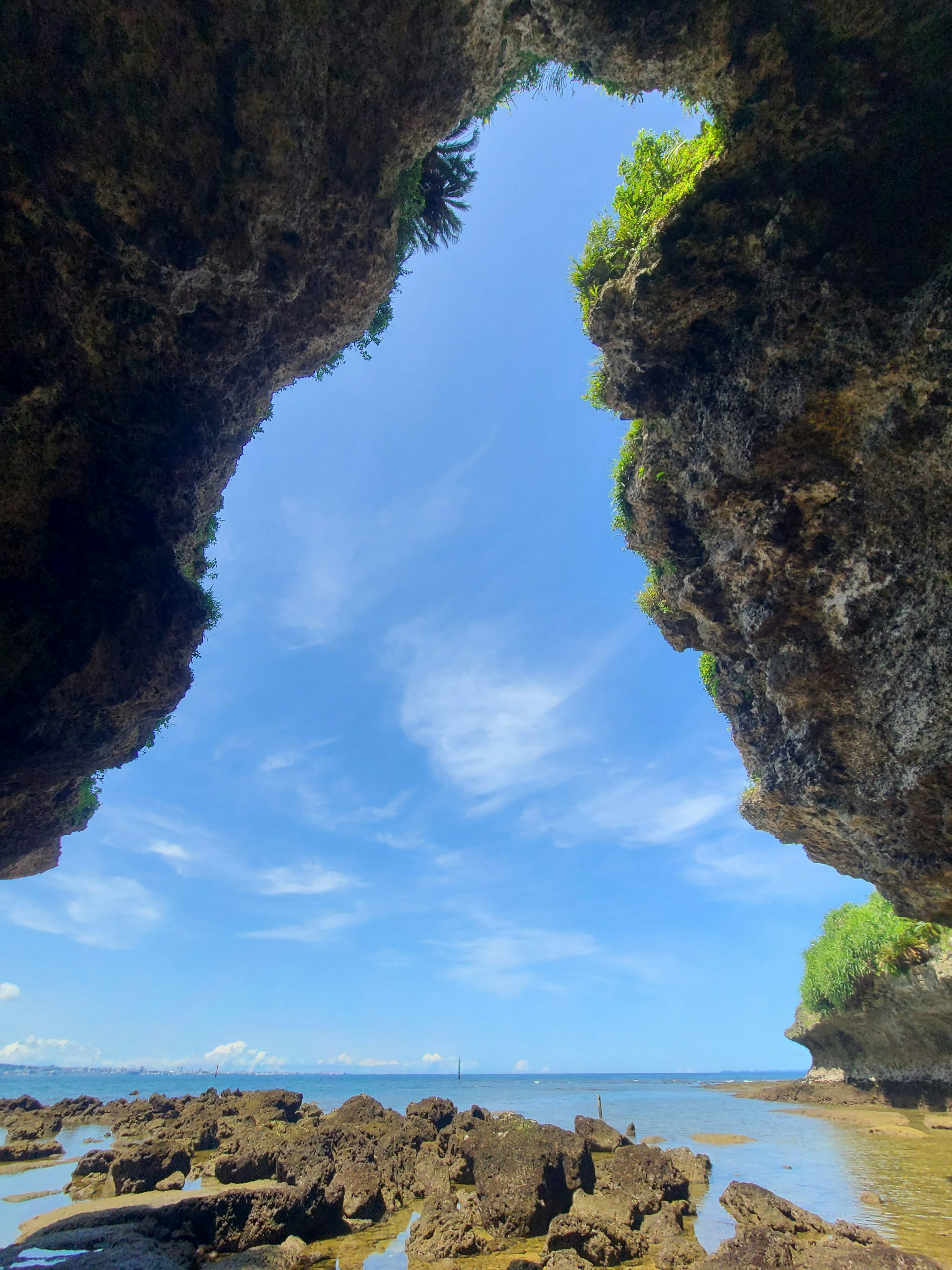 View of the sea through rocky formations under a blue sky