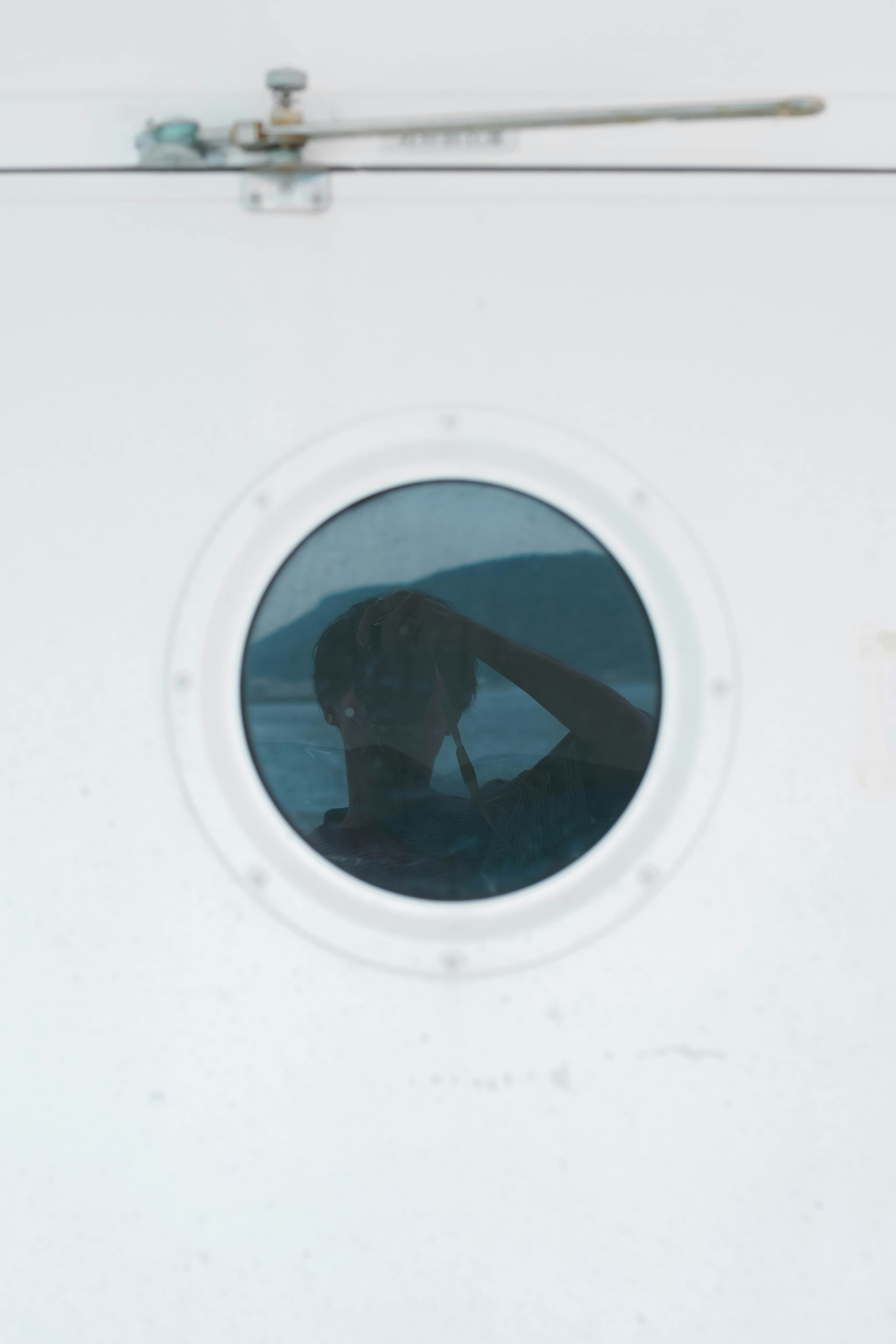 Reflection of a person in a round porthole on a white wall