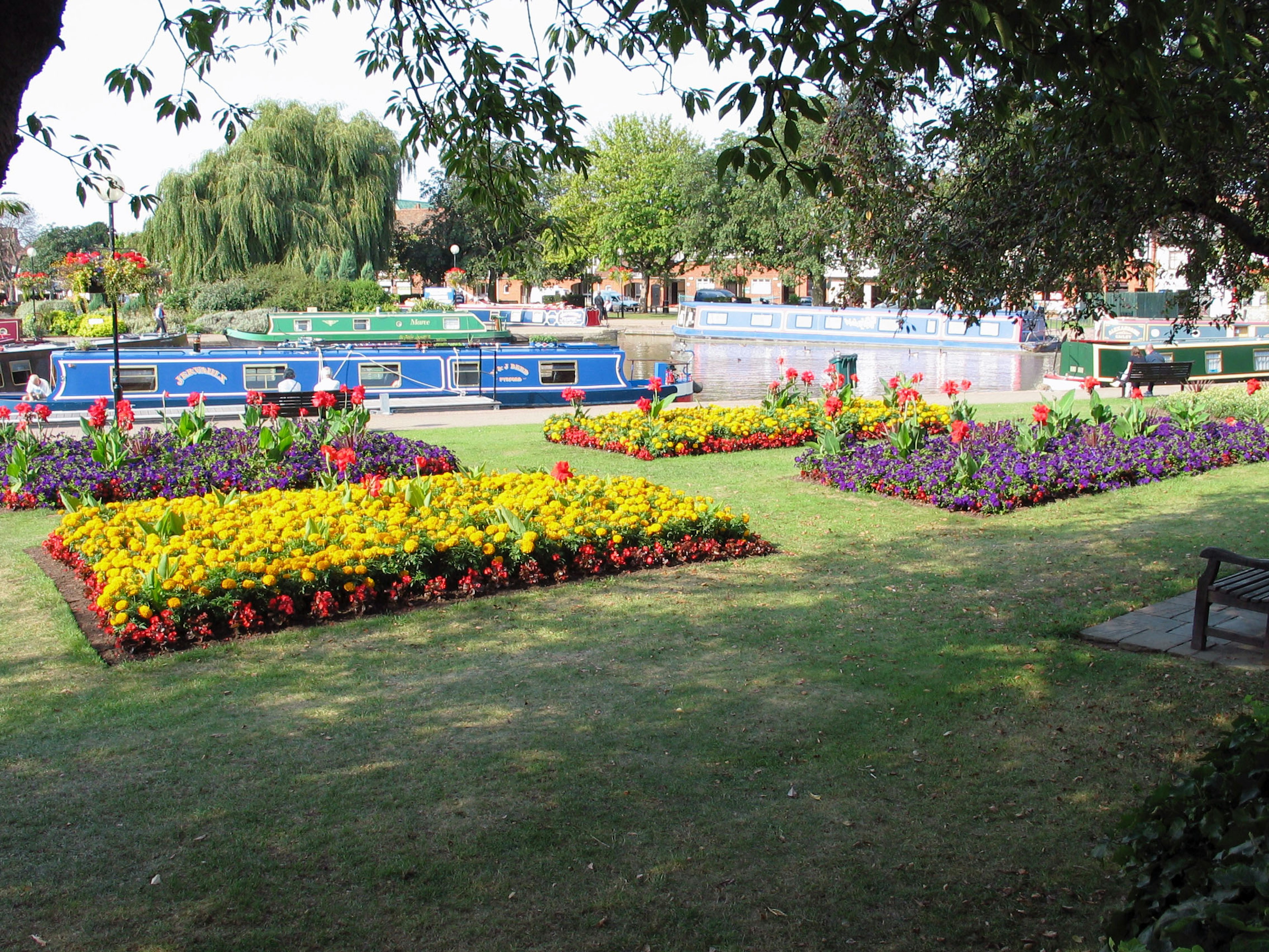 Colorful flowers in a park alongside a canal with boats