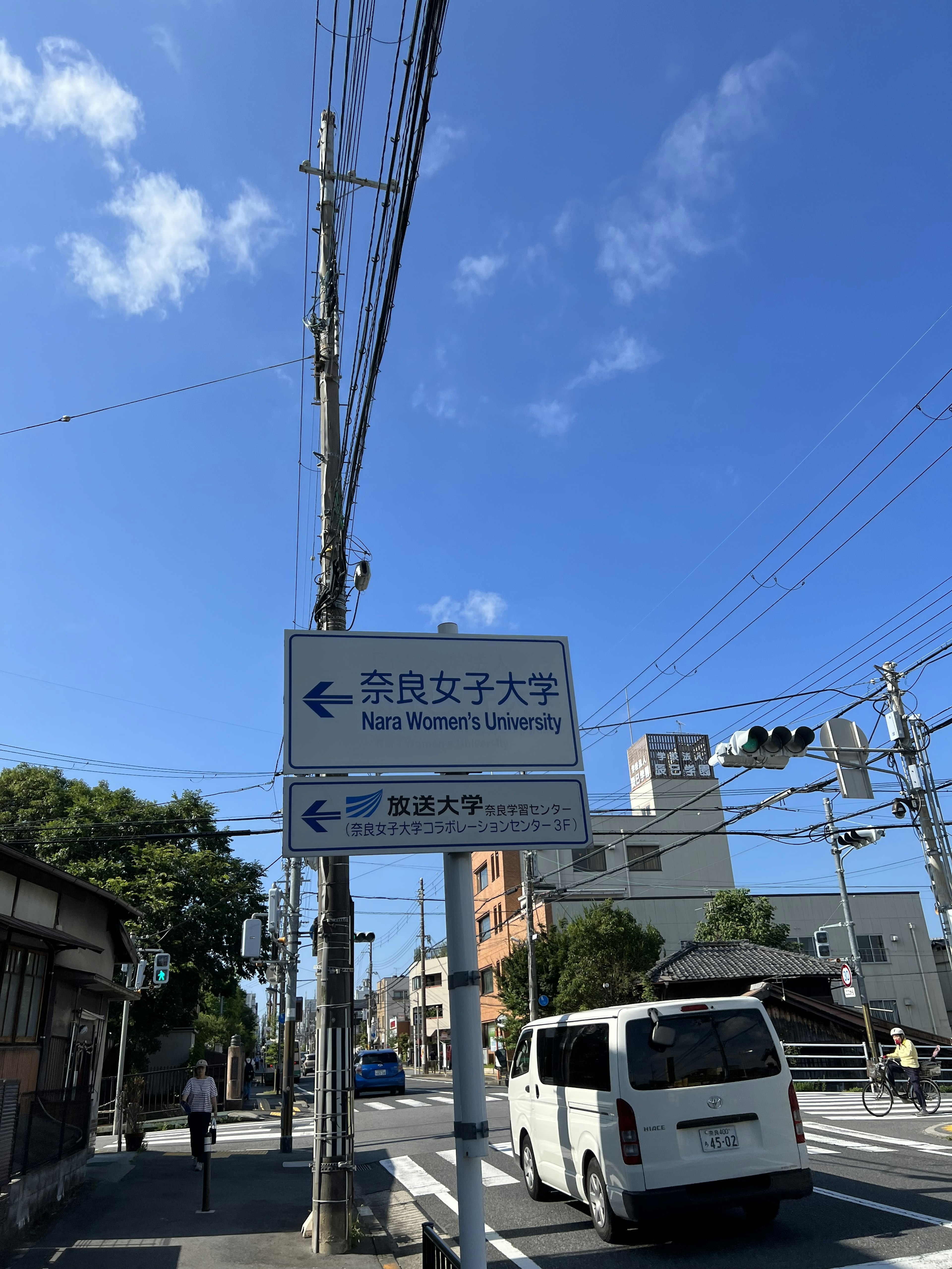 University sign under a clear blue sky with urban scenery