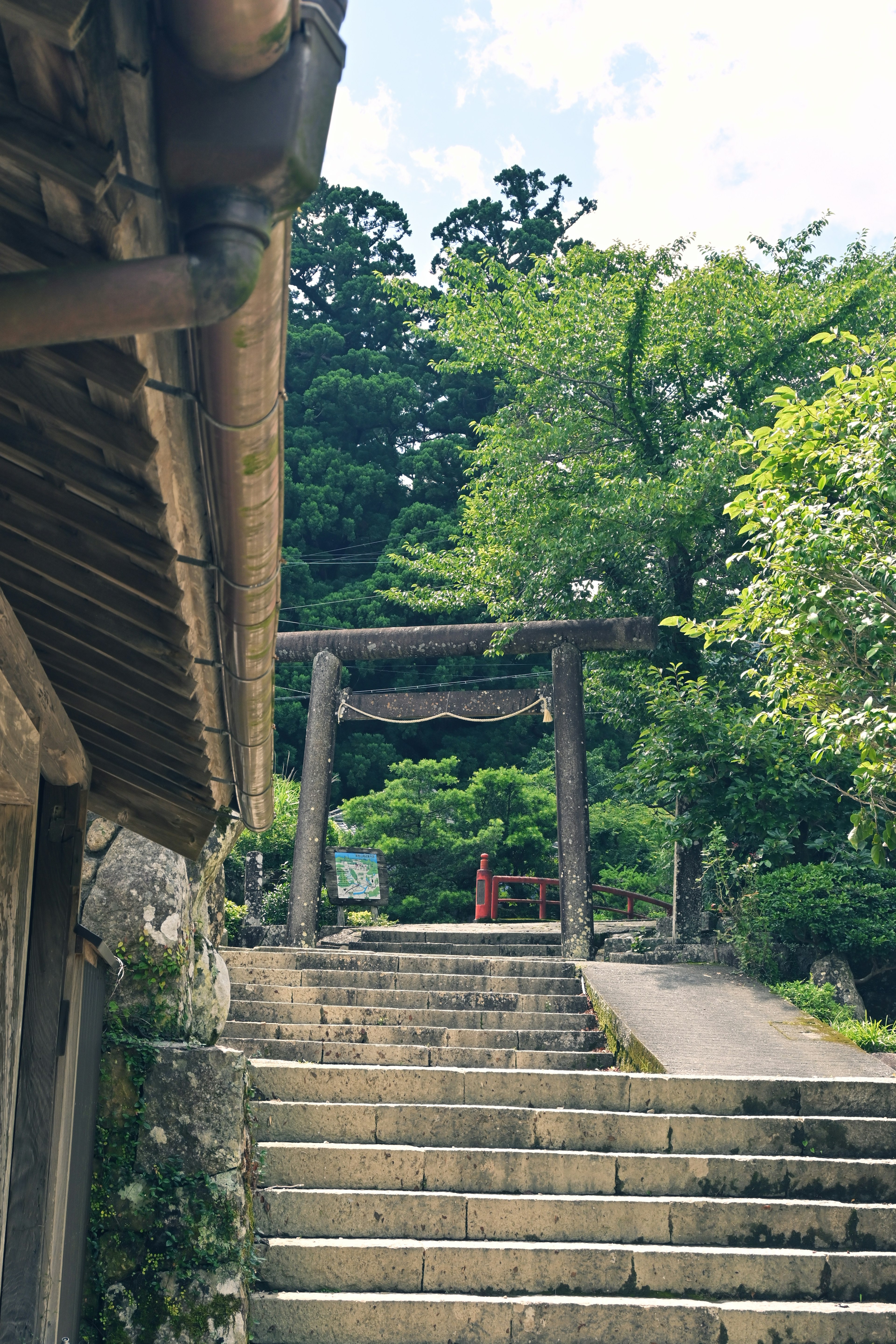 Stone steps leading to a torii gate in a lush green landscape