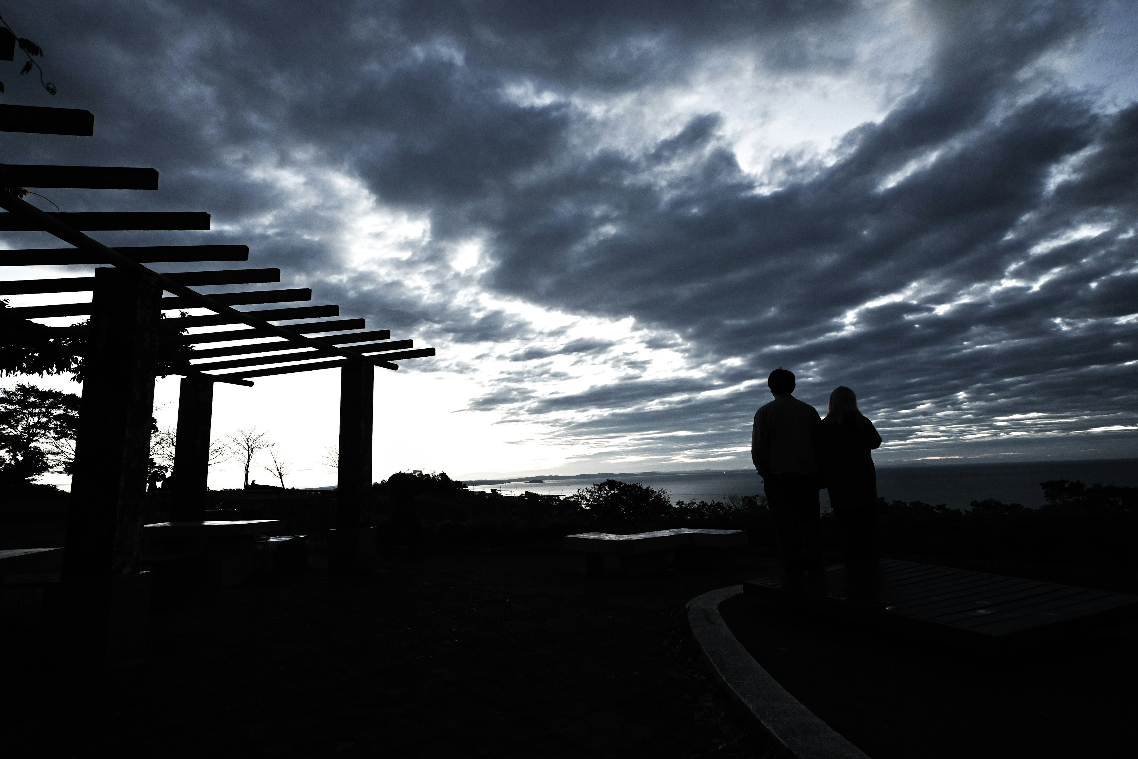 Silueta de una pareja contra un cielo crepuscular con una pérgola