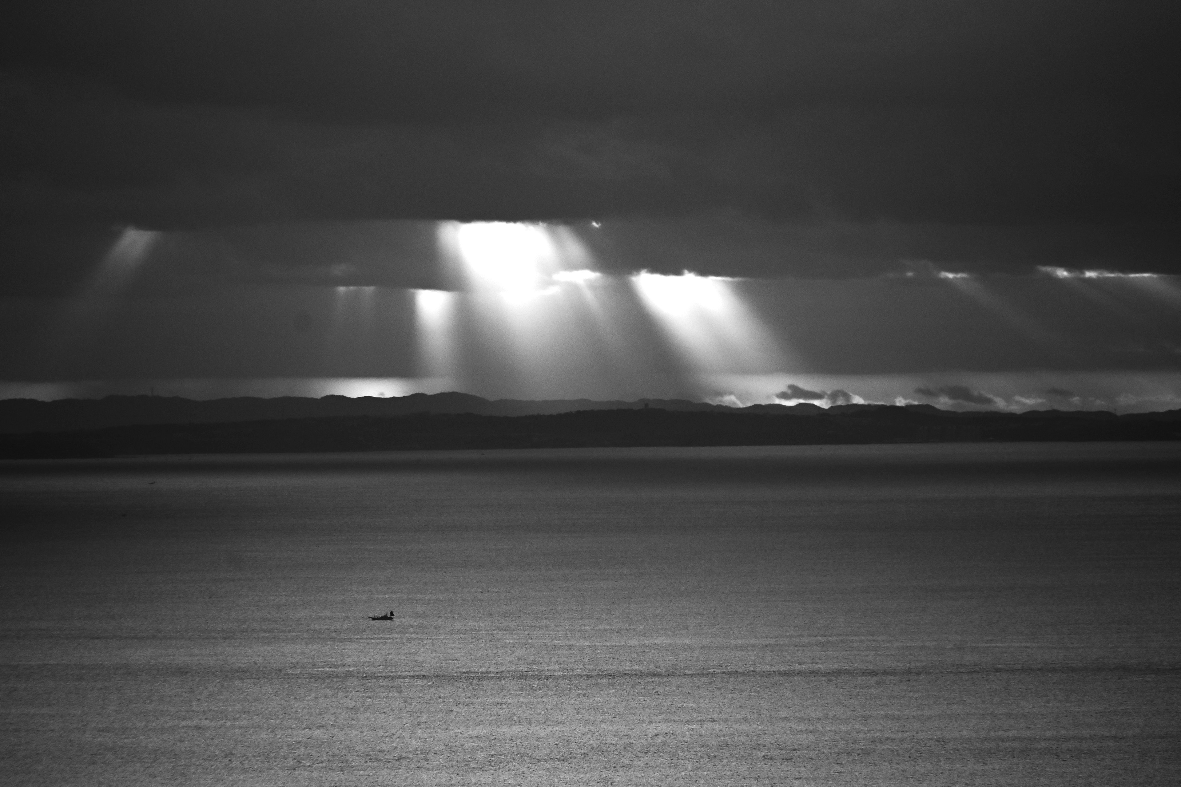 Rayos de luz que atraviesan nubes oscuras sobre un mar tranquilo