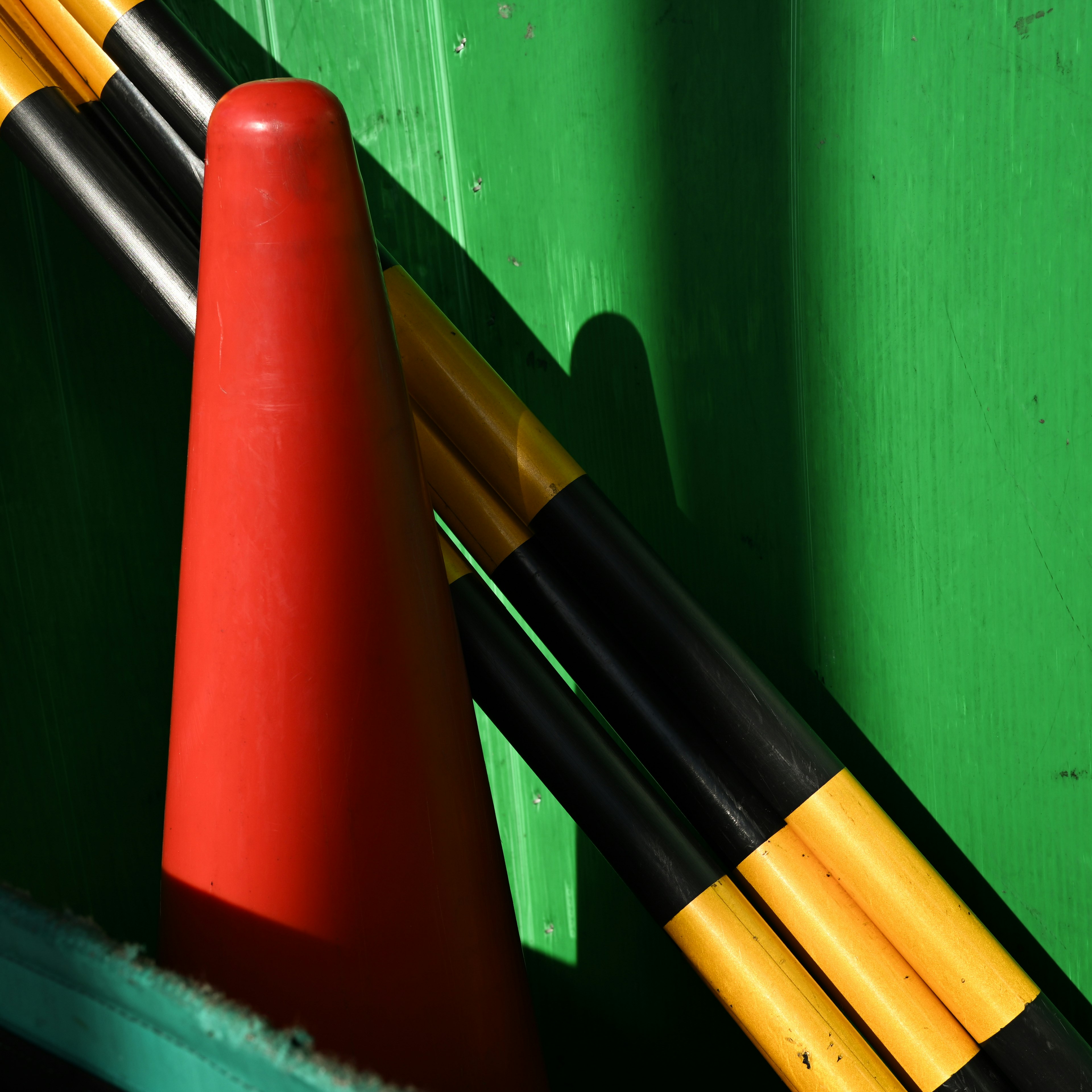 Red cone and black yellow poles against a green background