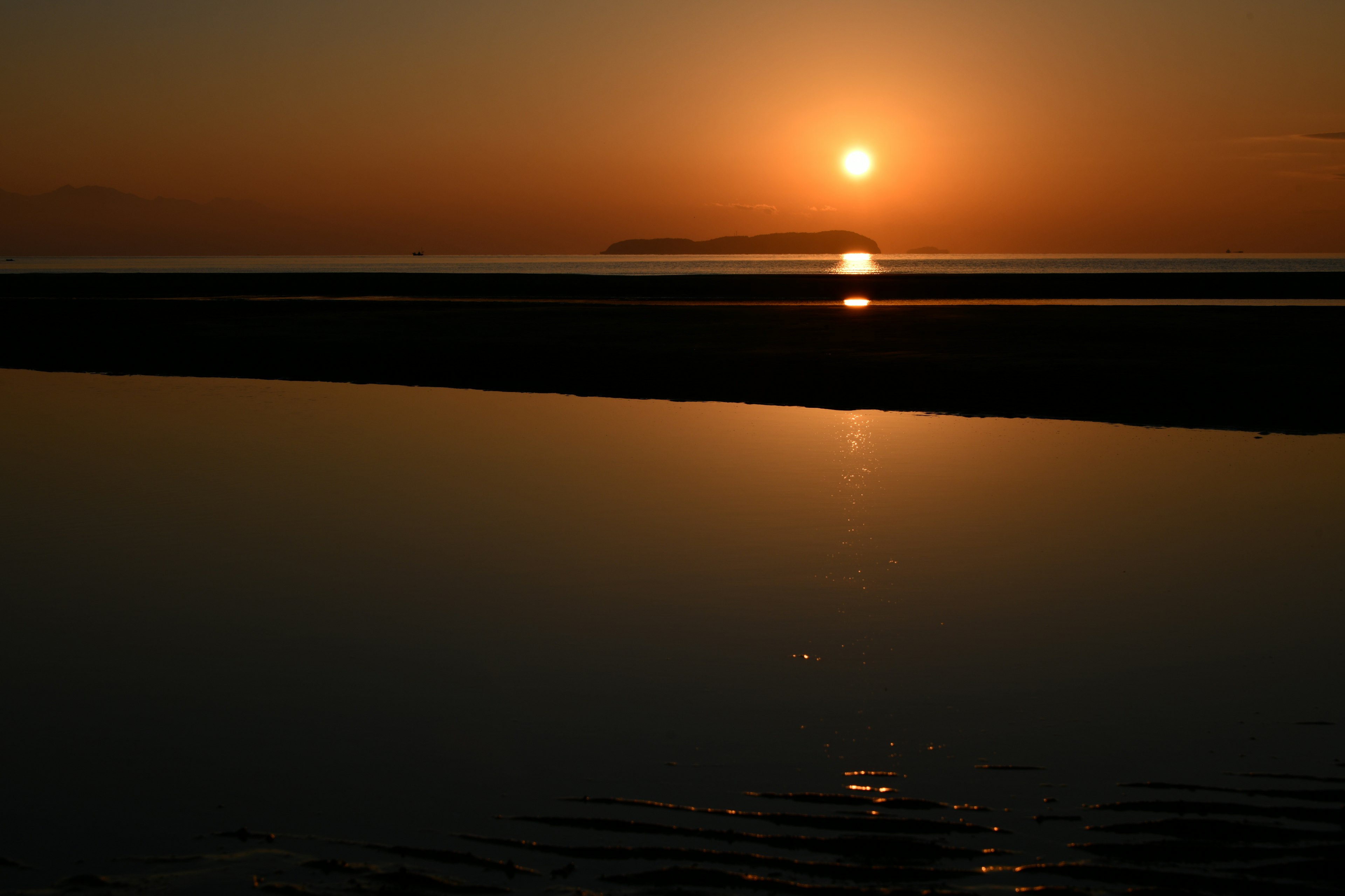 Schöne Landschaft des Sonnenuntergangs, der sich im Wasser spiegelt