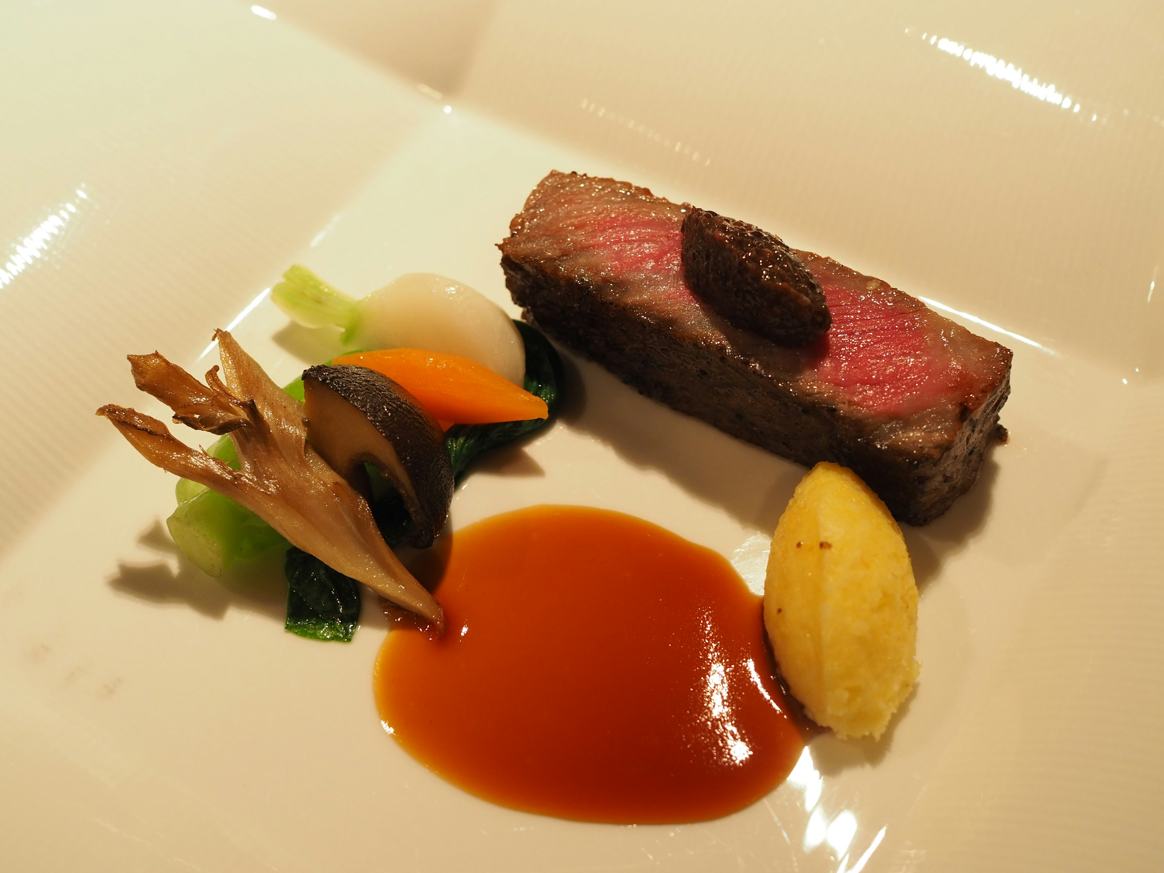 A beautifully plated meat dish accompanied by assorted vegetables