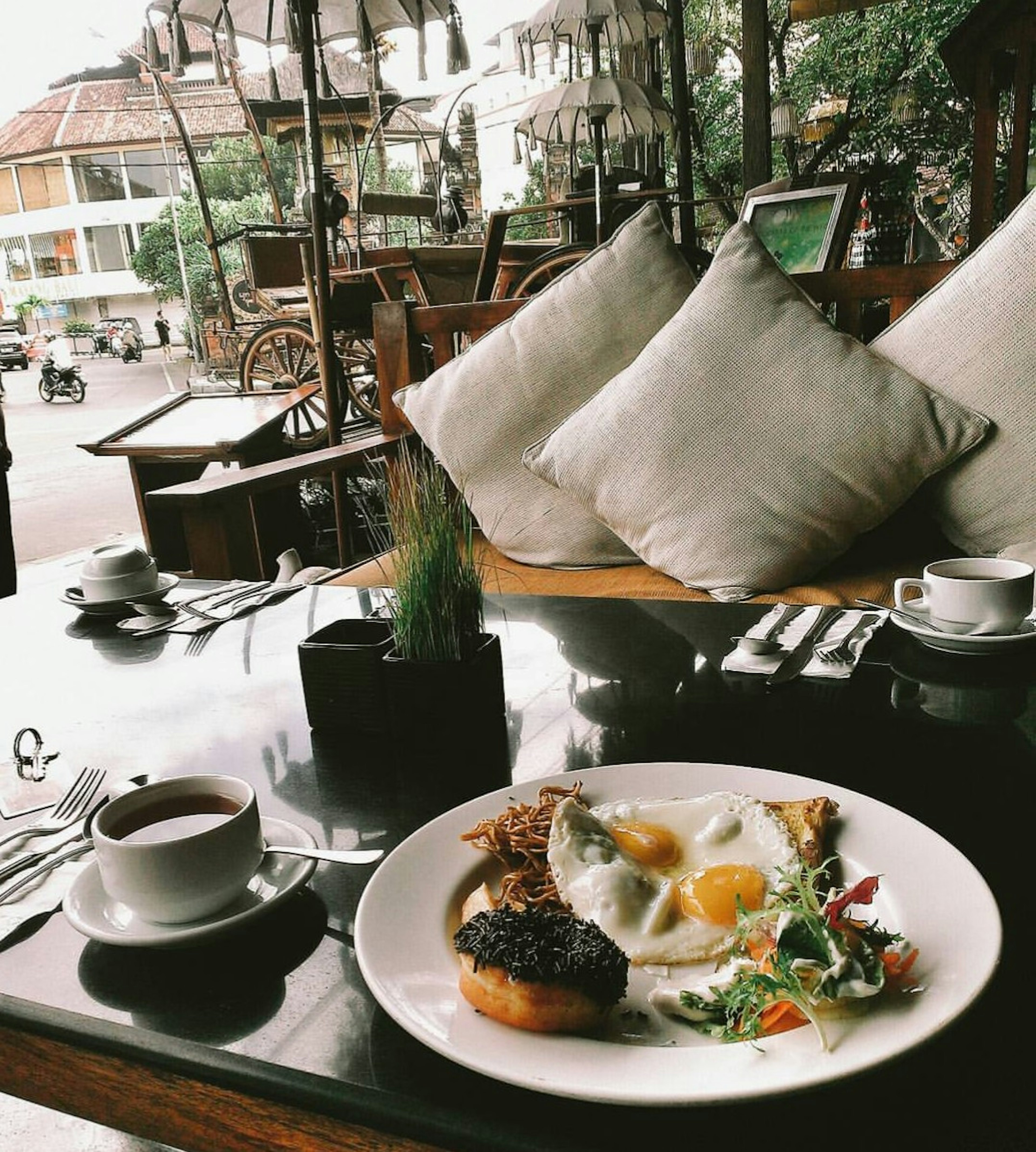 Breakfast plate with eggs and salad on a cafe table with a coffee cup and cushioned seating in the background