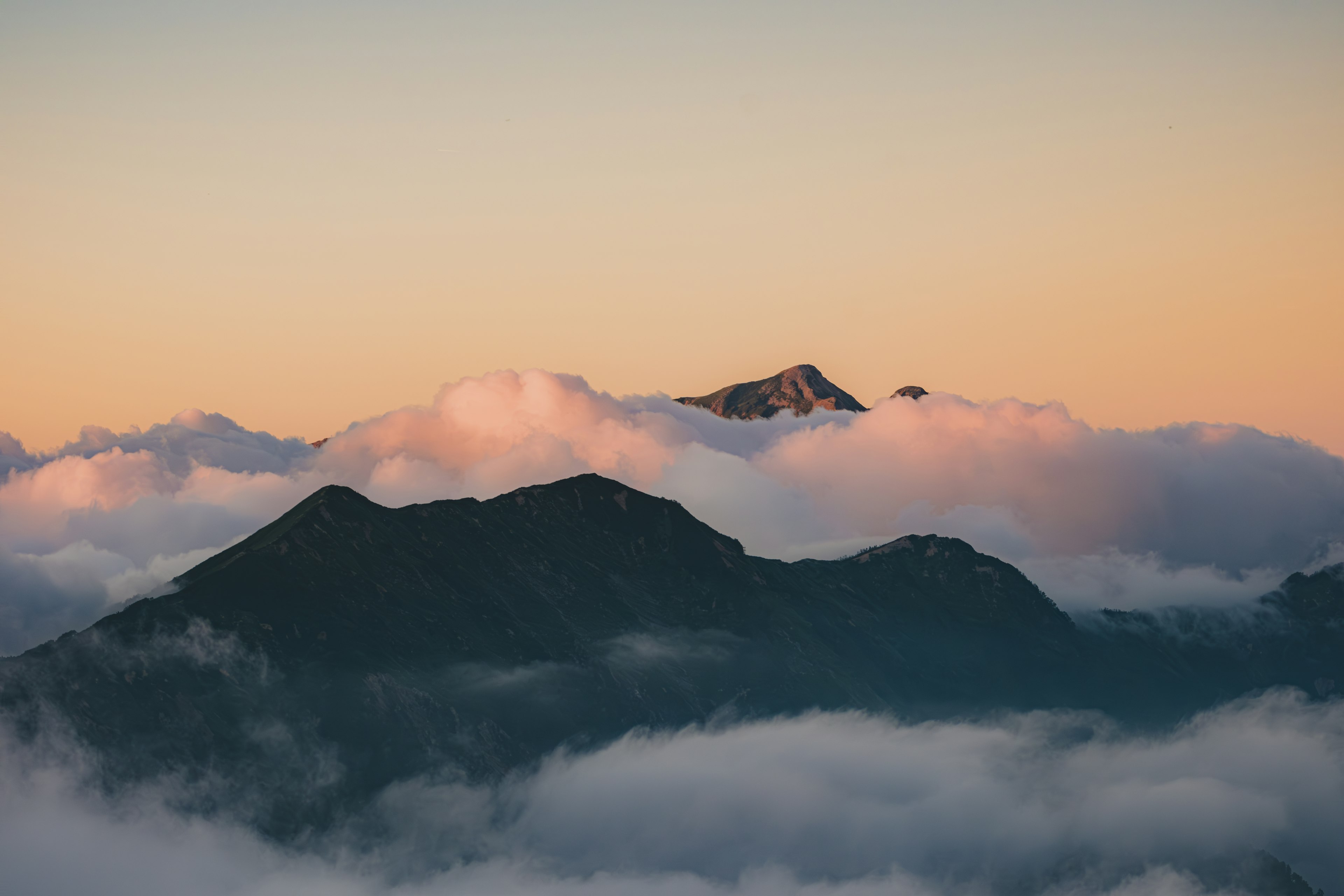 Vue panoramique de montagnes enveloppées de nuages au coucher du soleil