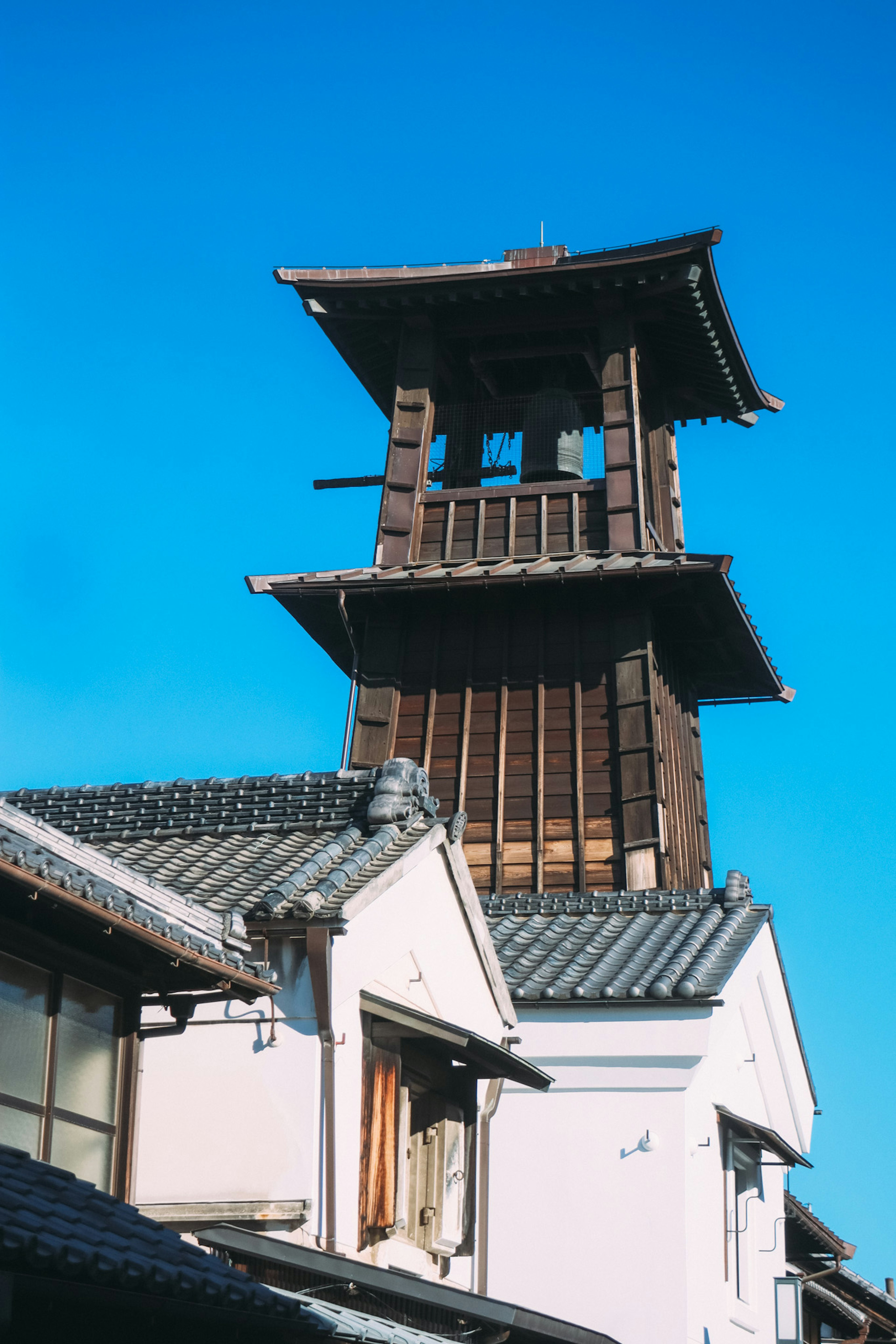 Wooden clock tower under a blue sky with traditional buildings