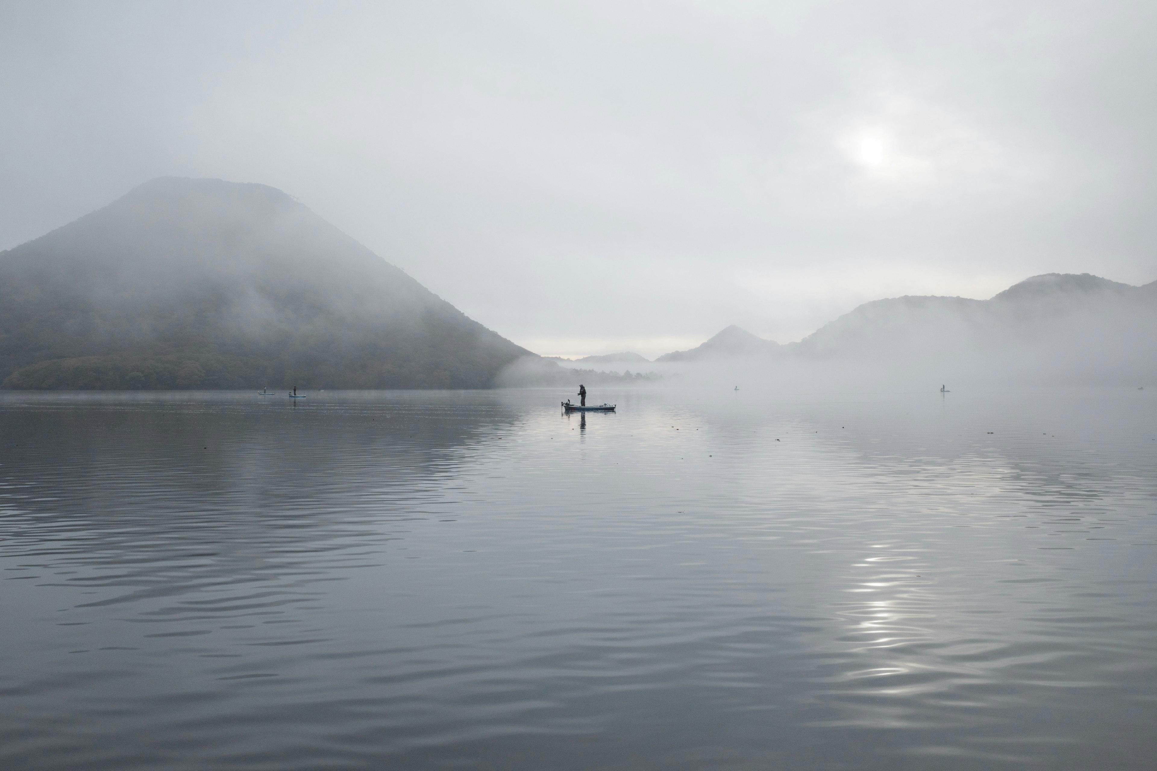 Ein ruhiger See mit einem kleinen Boot, das im Nebel treibt