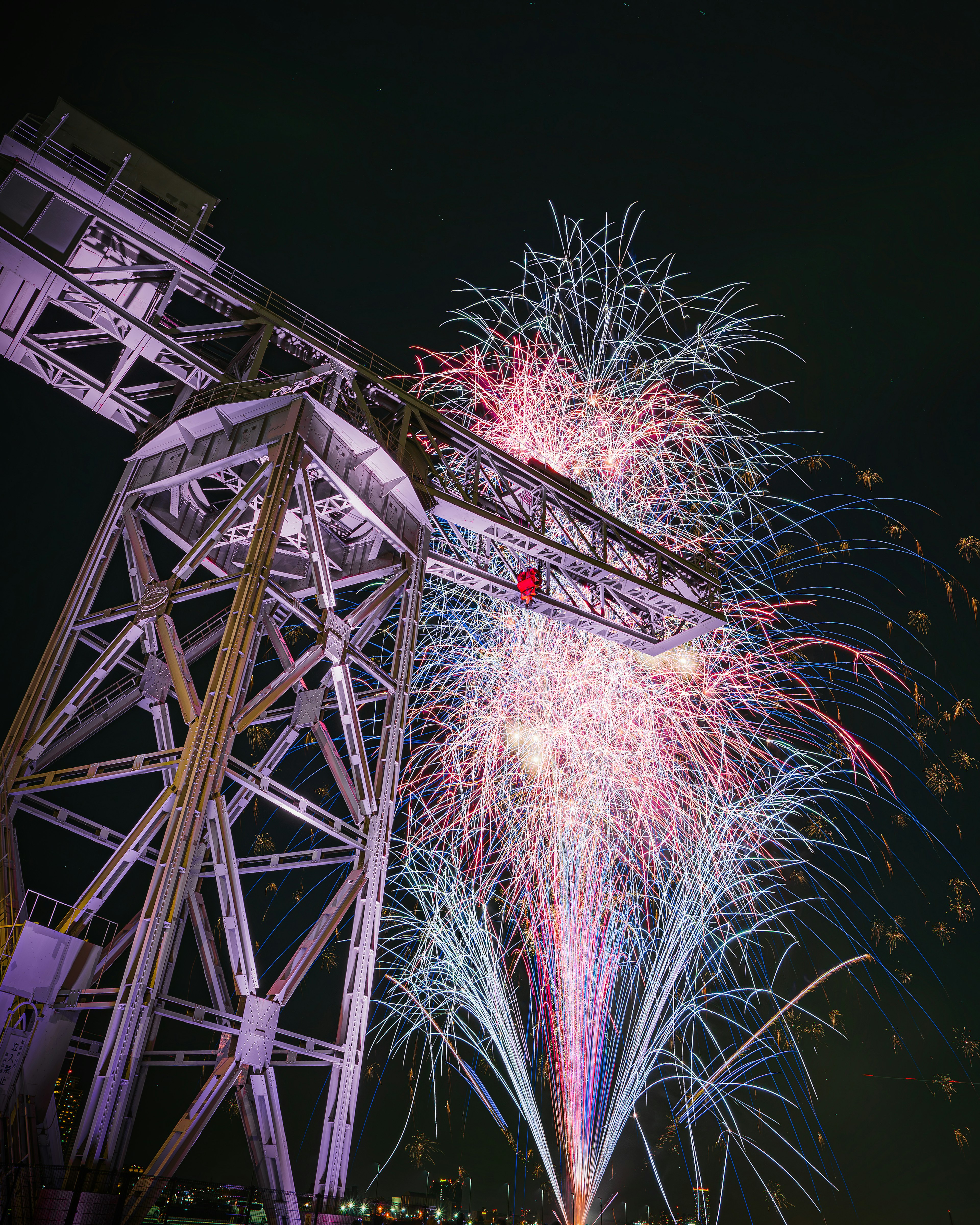 Fuegos artificiales coloridos estallando desde una grúa morada contra un cielo nocturno oscuro