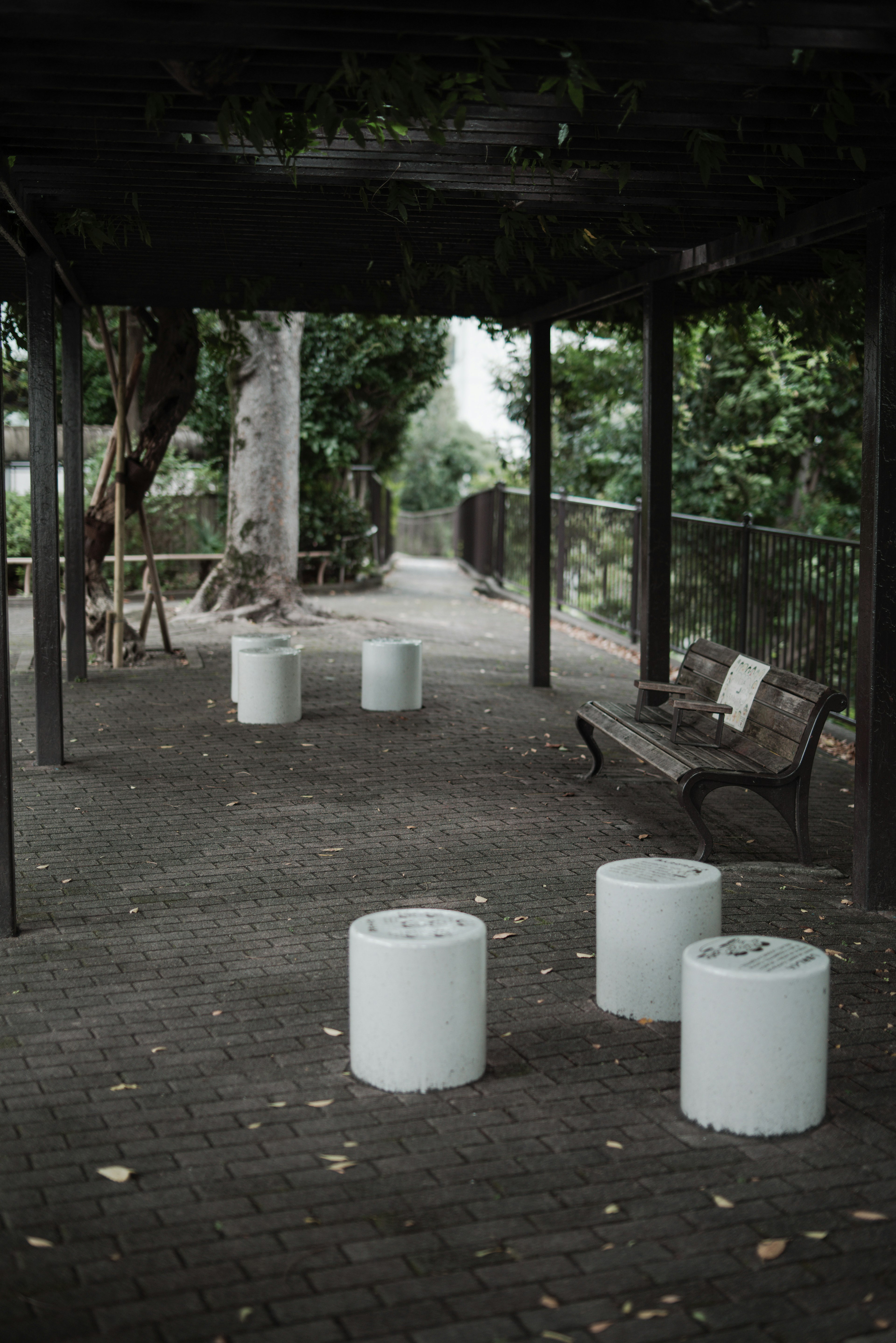 White cylindrical stools arranged in a park area surrounded by greenery