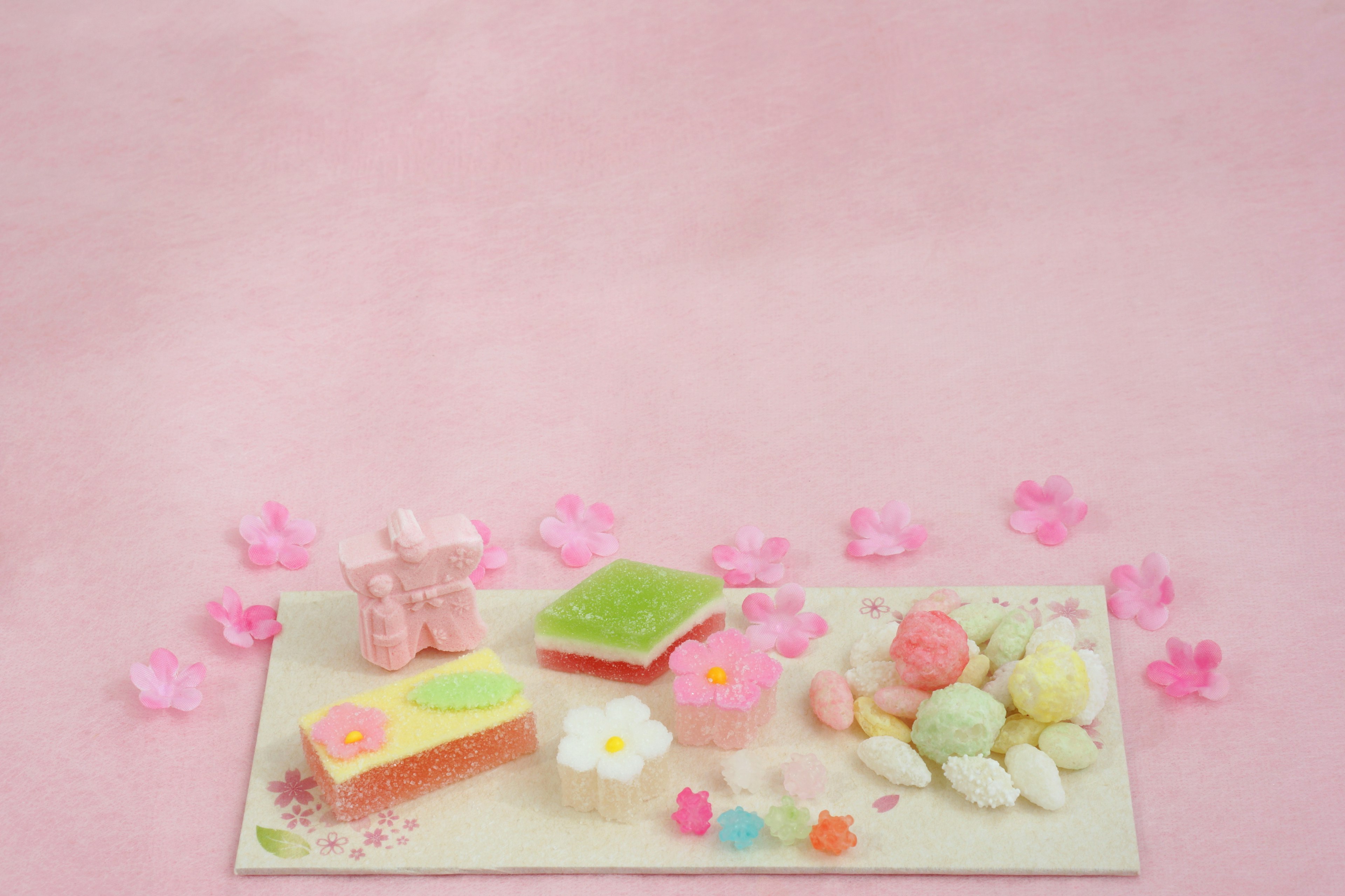 Colorful Japanese sweets arranged on a platter with pink cherry blossom petals