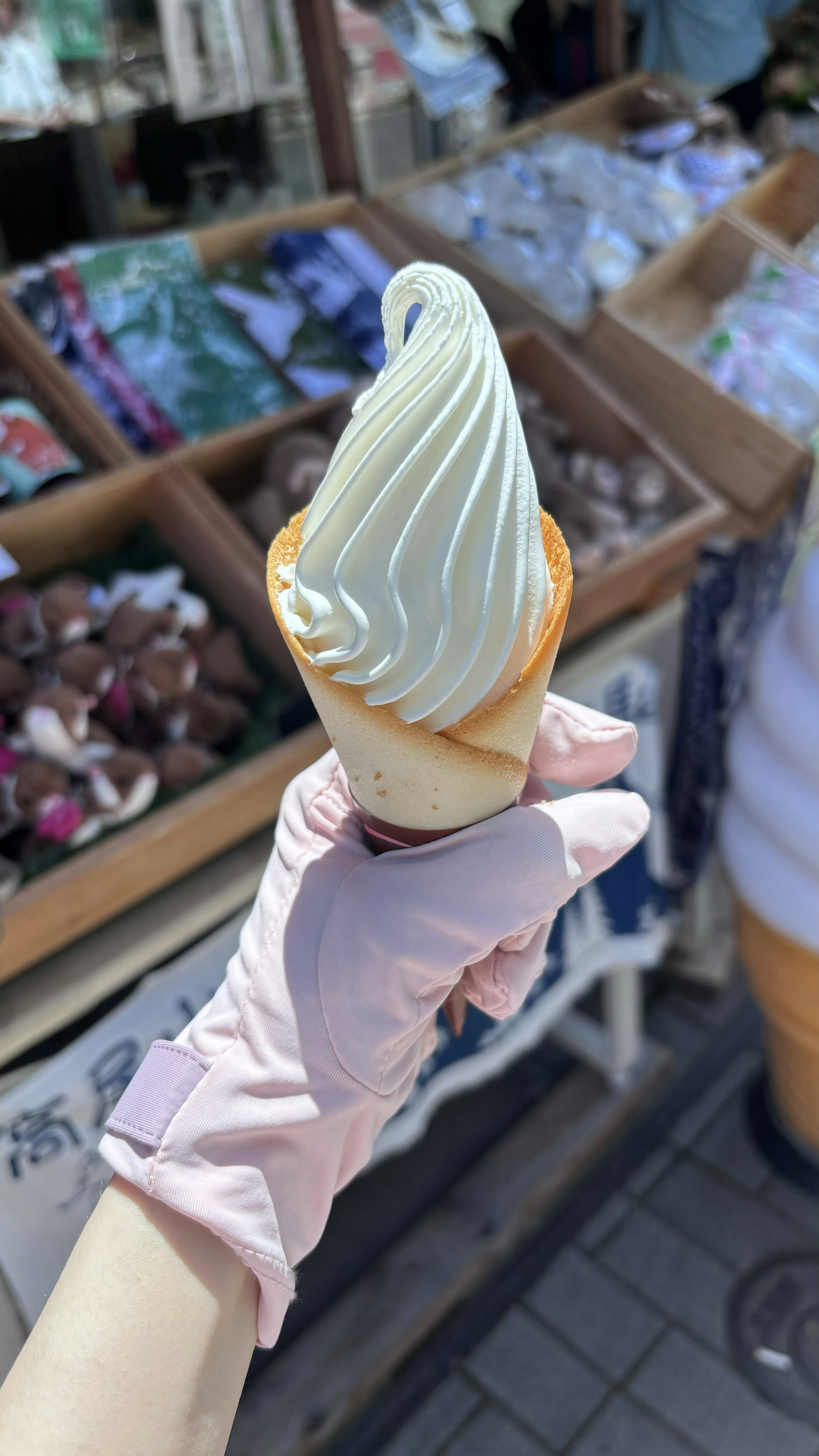 Una mano sosteniendo helado suave con artículos coloridos en el fondo