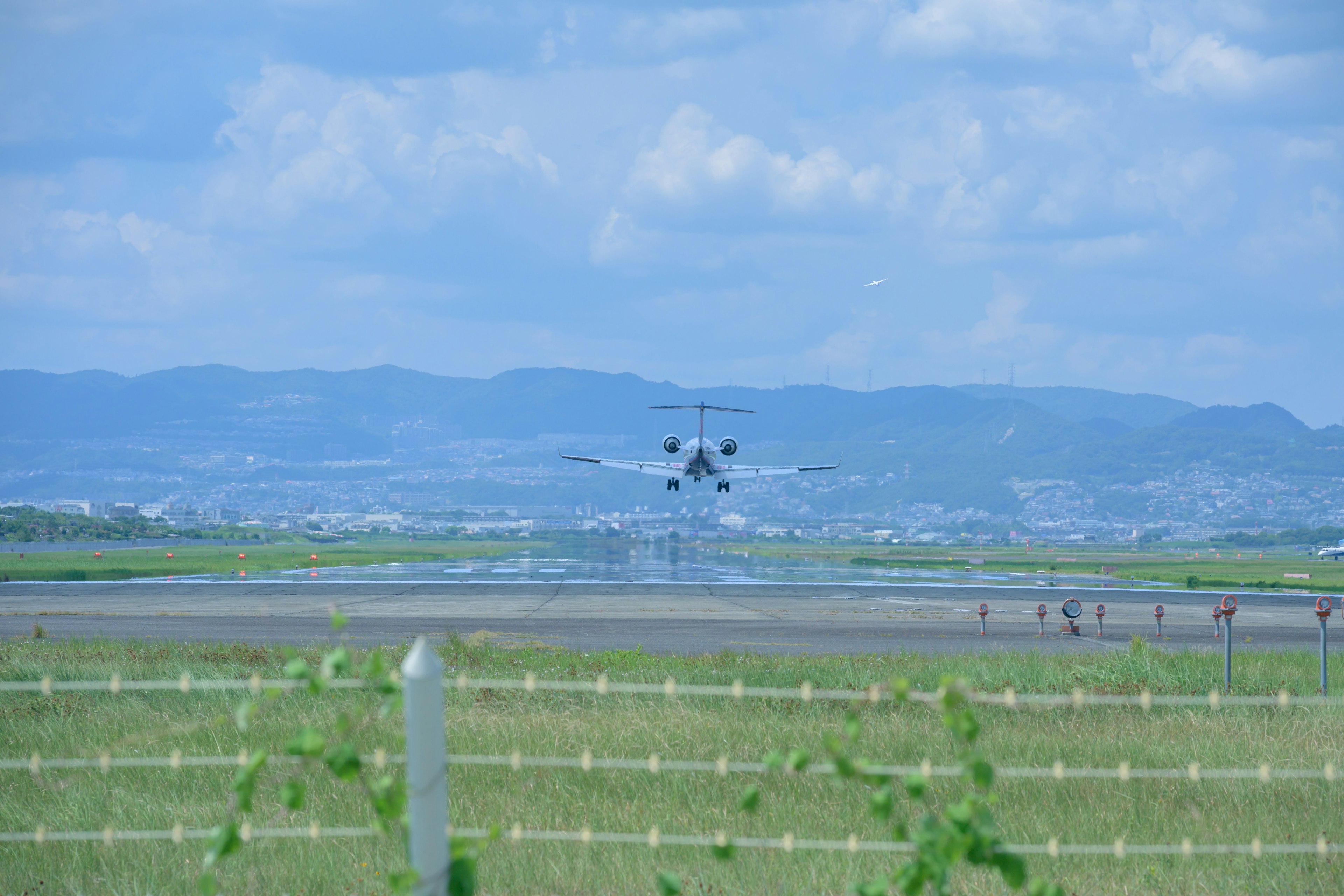 Aereo in atterraggio sulla pista con cielo blu e montagne sullo sfondo