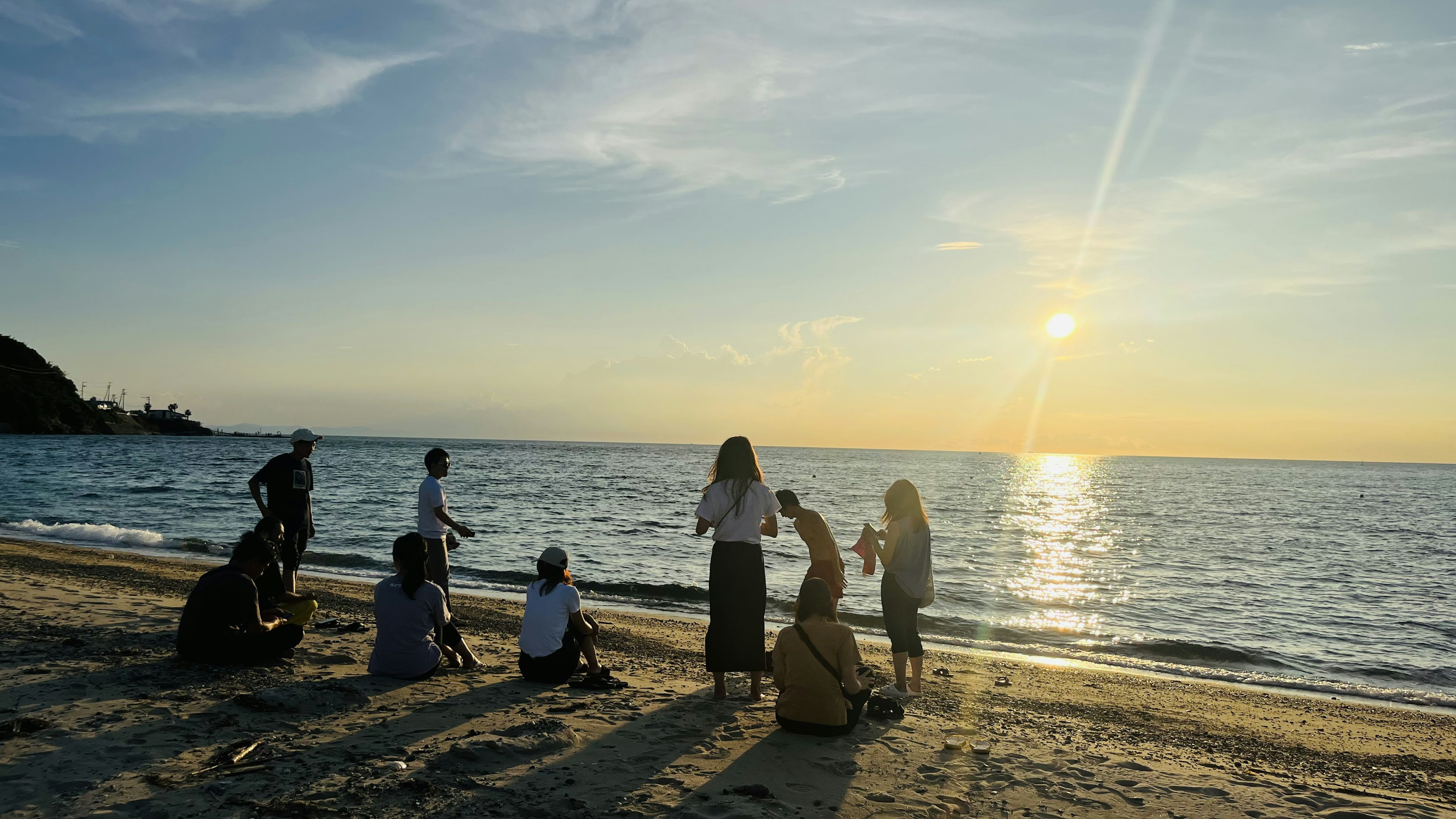 海辺で夕日を見つめる人々の集まり