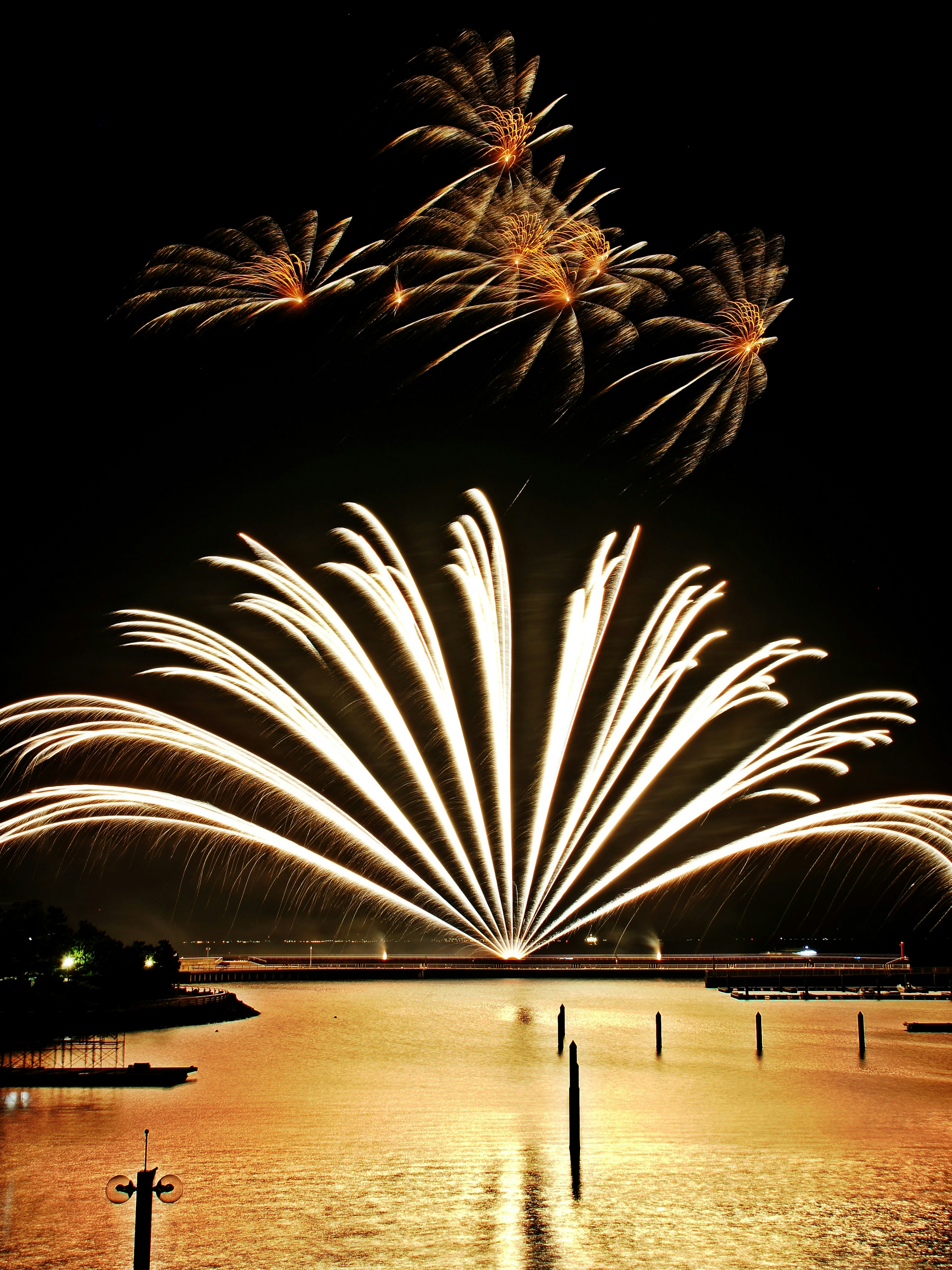 Espectacular exhibición de fuegos artificiales en el cielo nocturno con reflejos en el agua