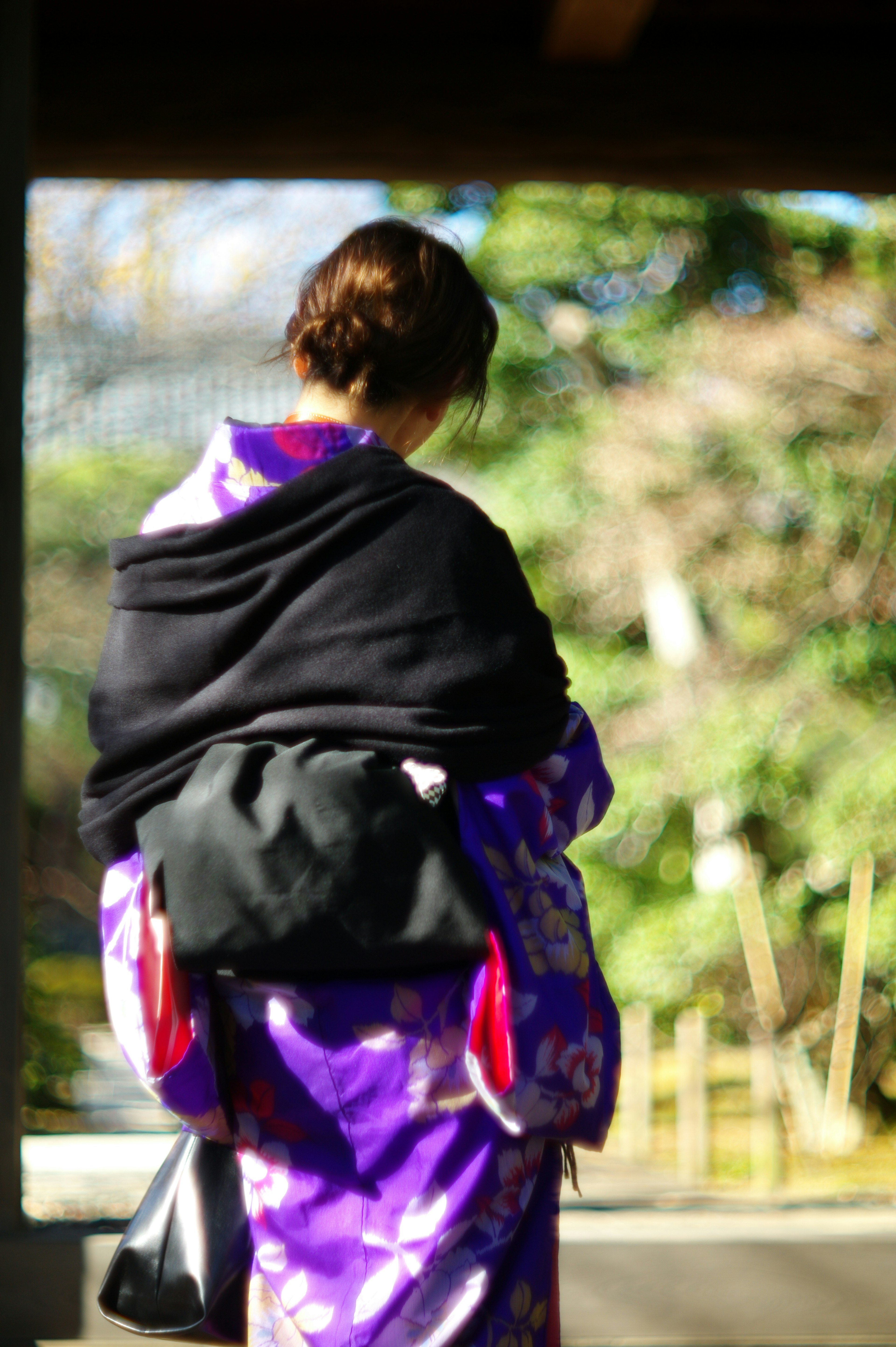 Wanita dengan kimono ungu dan selendang hitam dilihat dari belakang