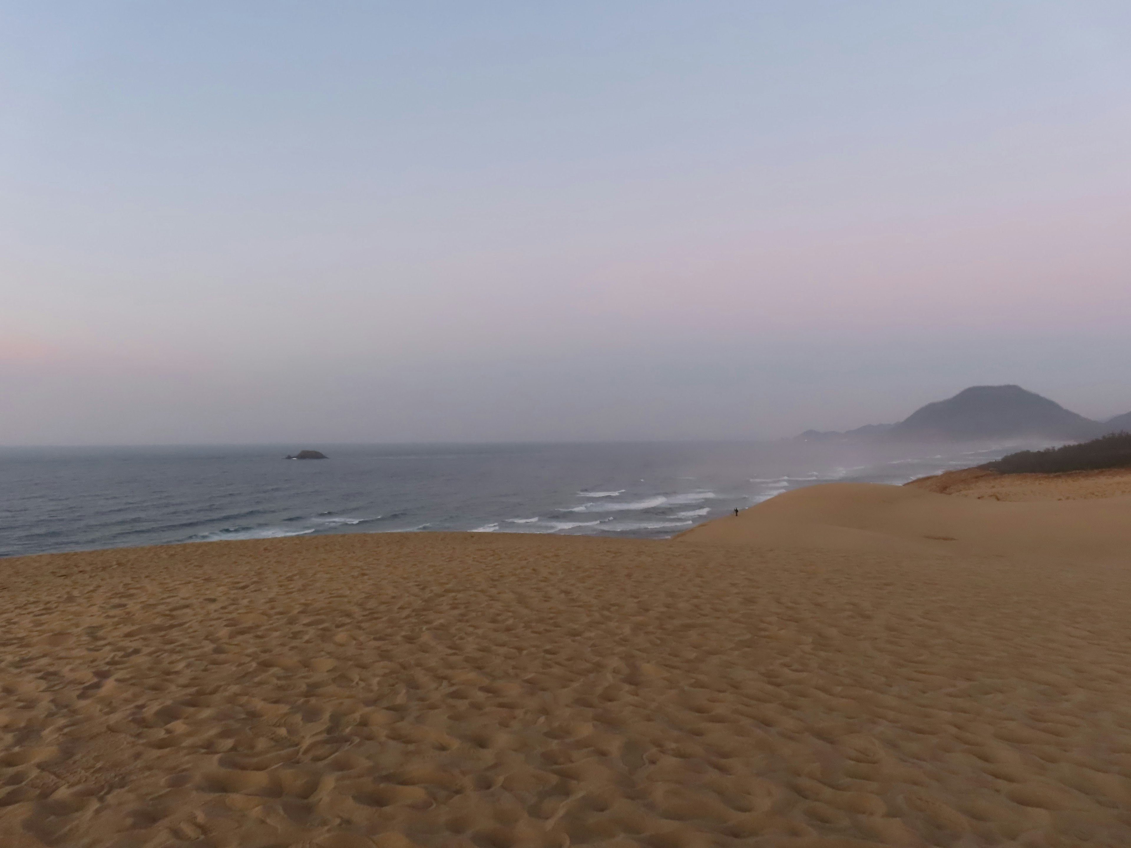 Coastal sand beach with gentle waves soft colors in the twilight sky