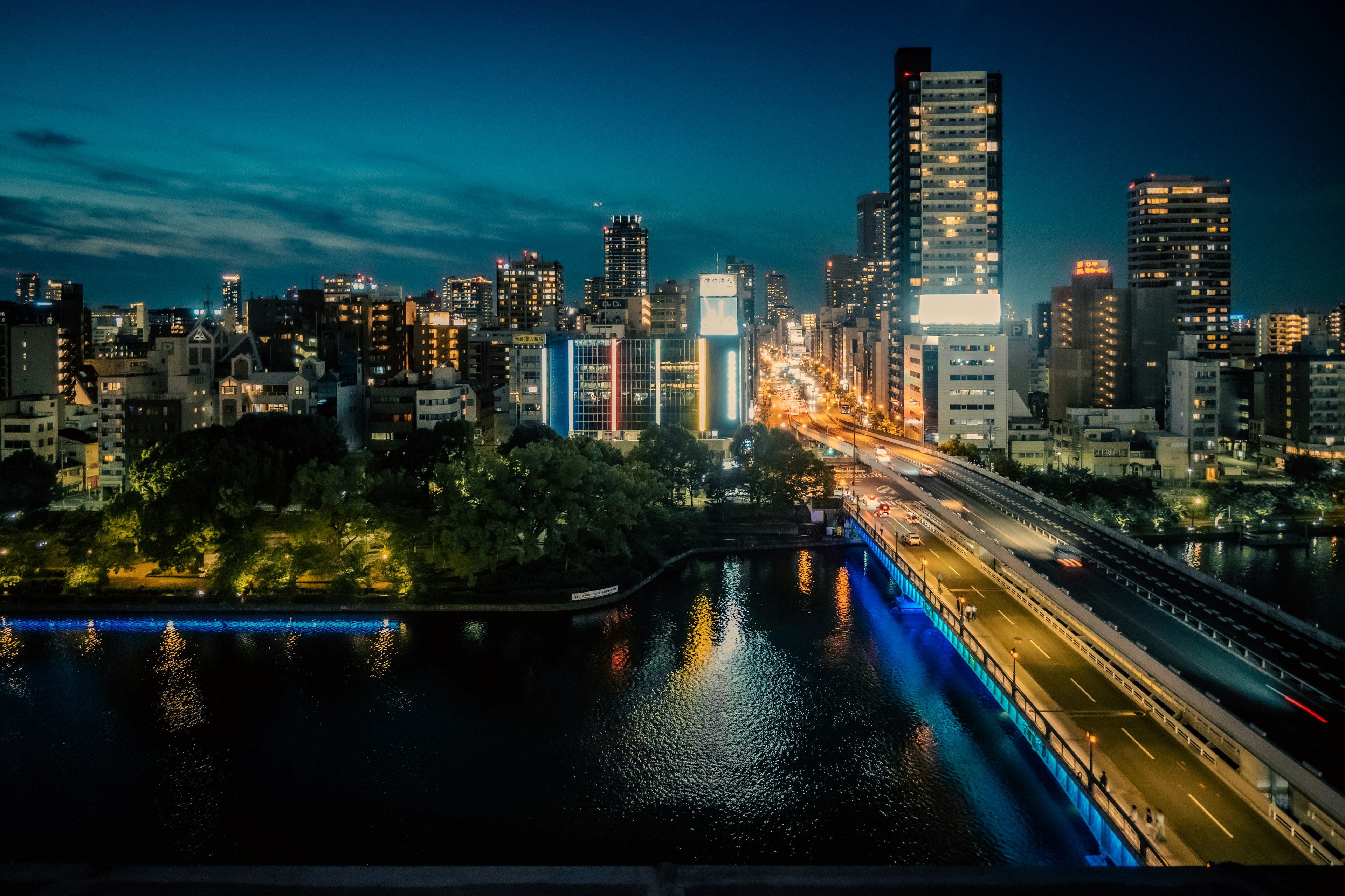 Night cityscape featuring skyscrapers and a river illuminated by bridge lights