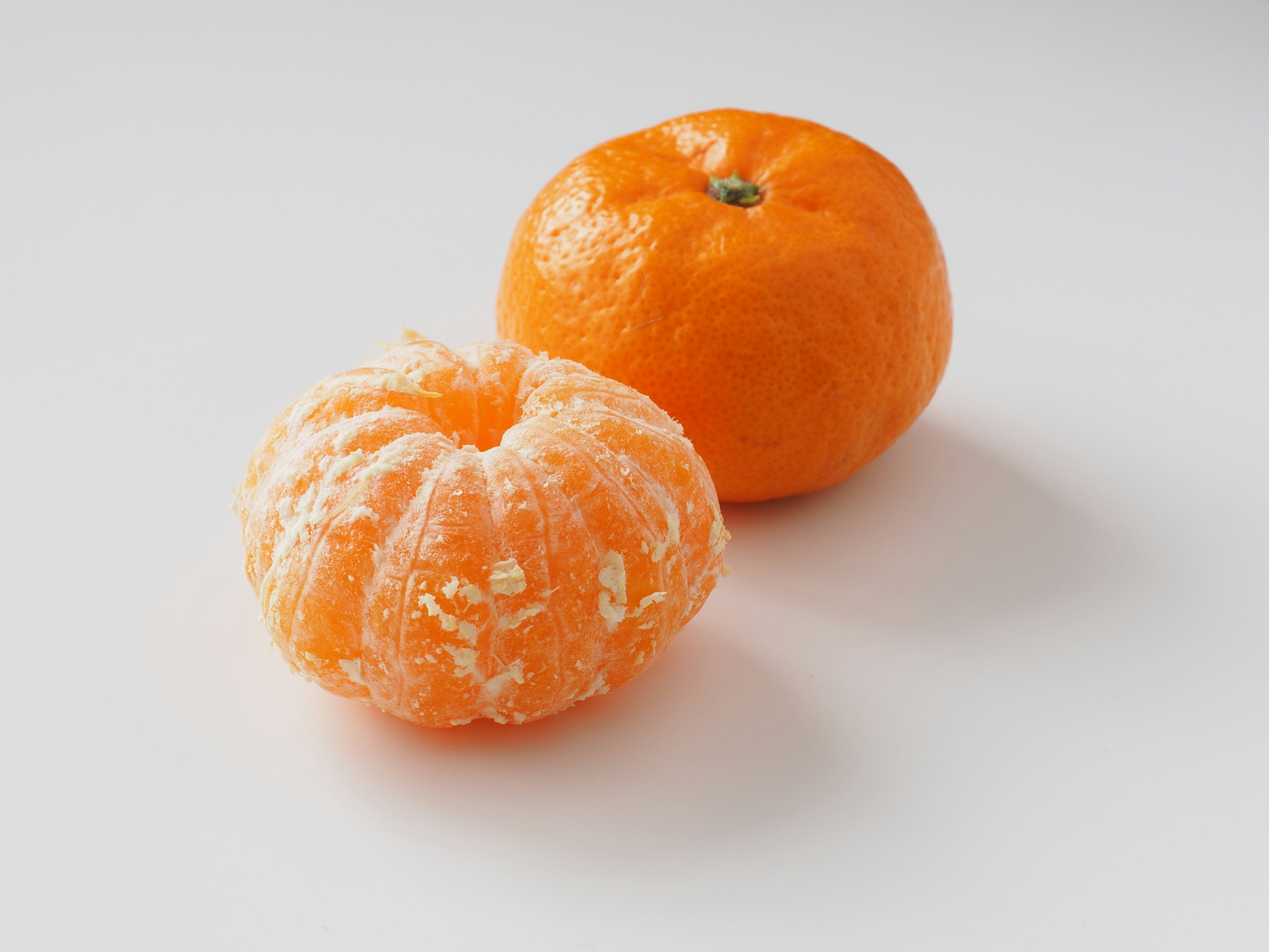 Two citrus fruits in orange color one with peeled skin