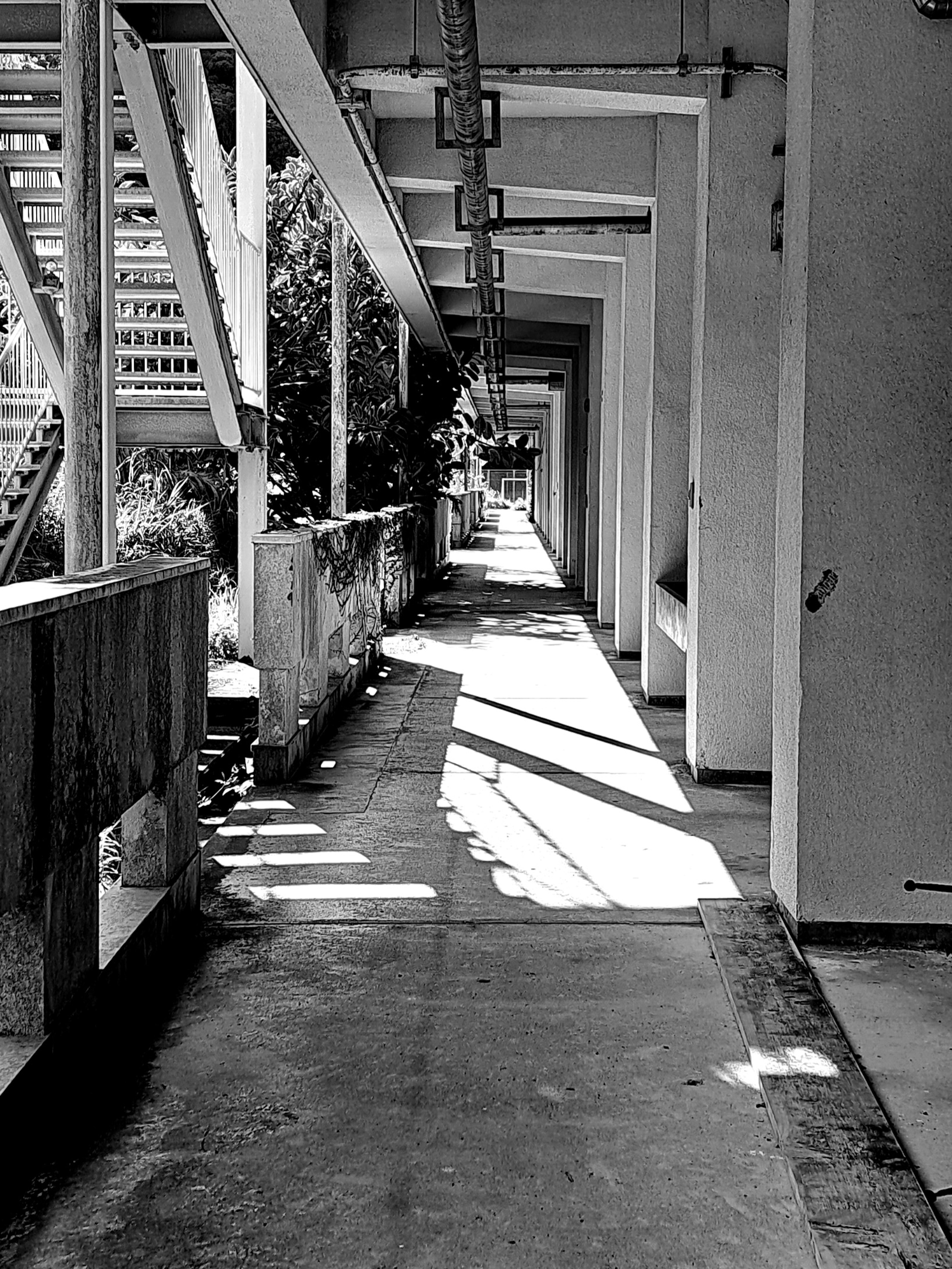 Black and white photo of a corridor featuring linear architecture and shadows