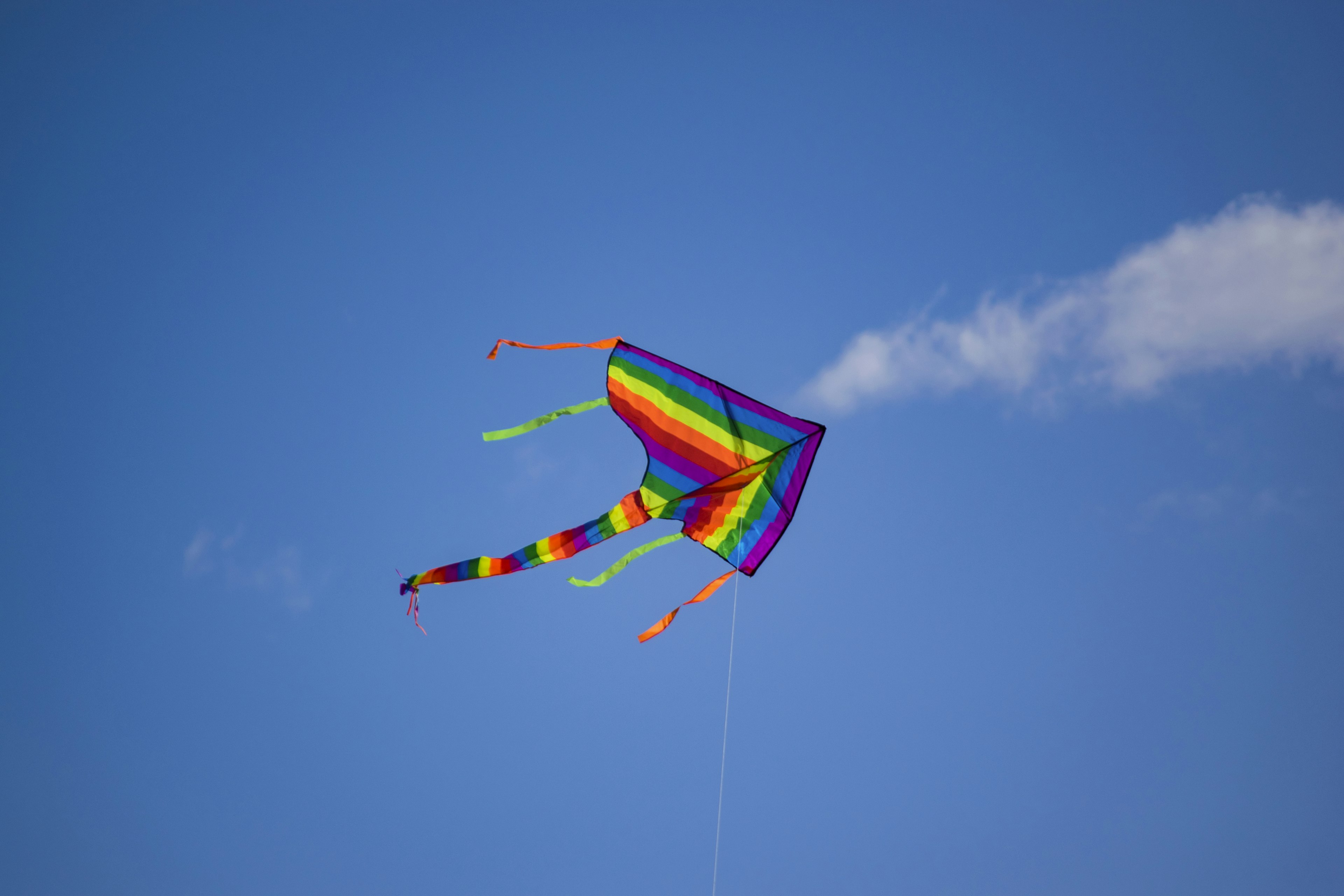 Colorful rainbow kite flying in a blue sky