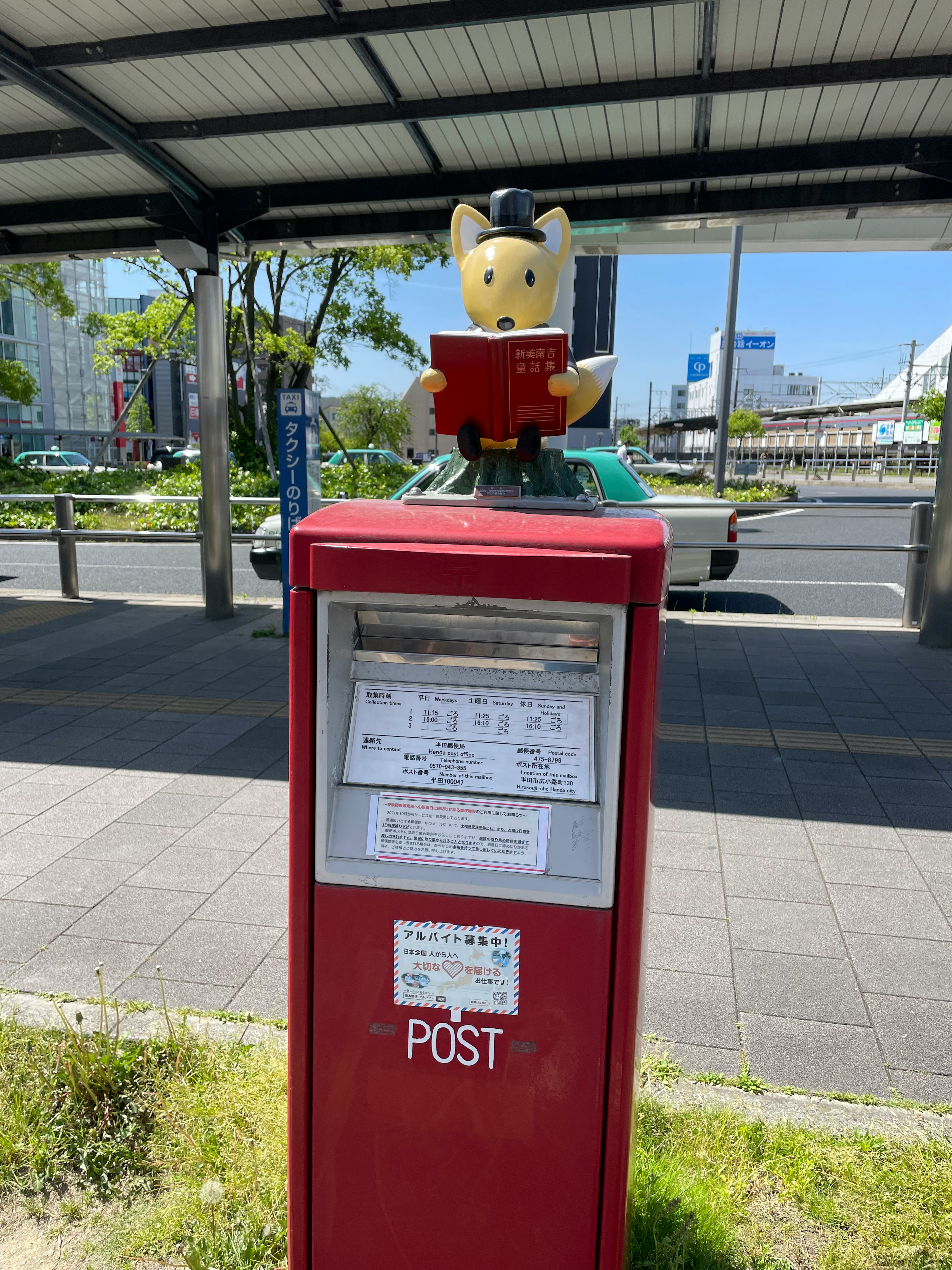 A red mailbox featuring a character reading a book on top