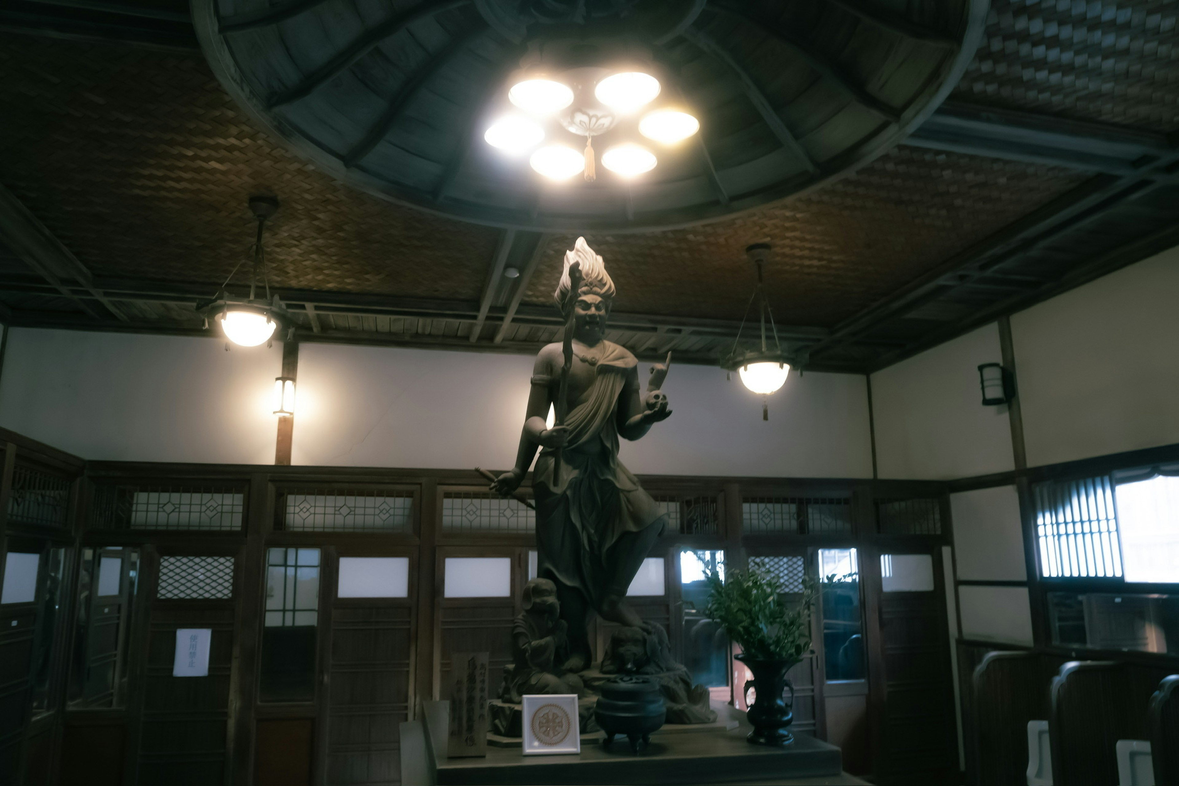 Indoor statue of a deity with lighting fixtures above